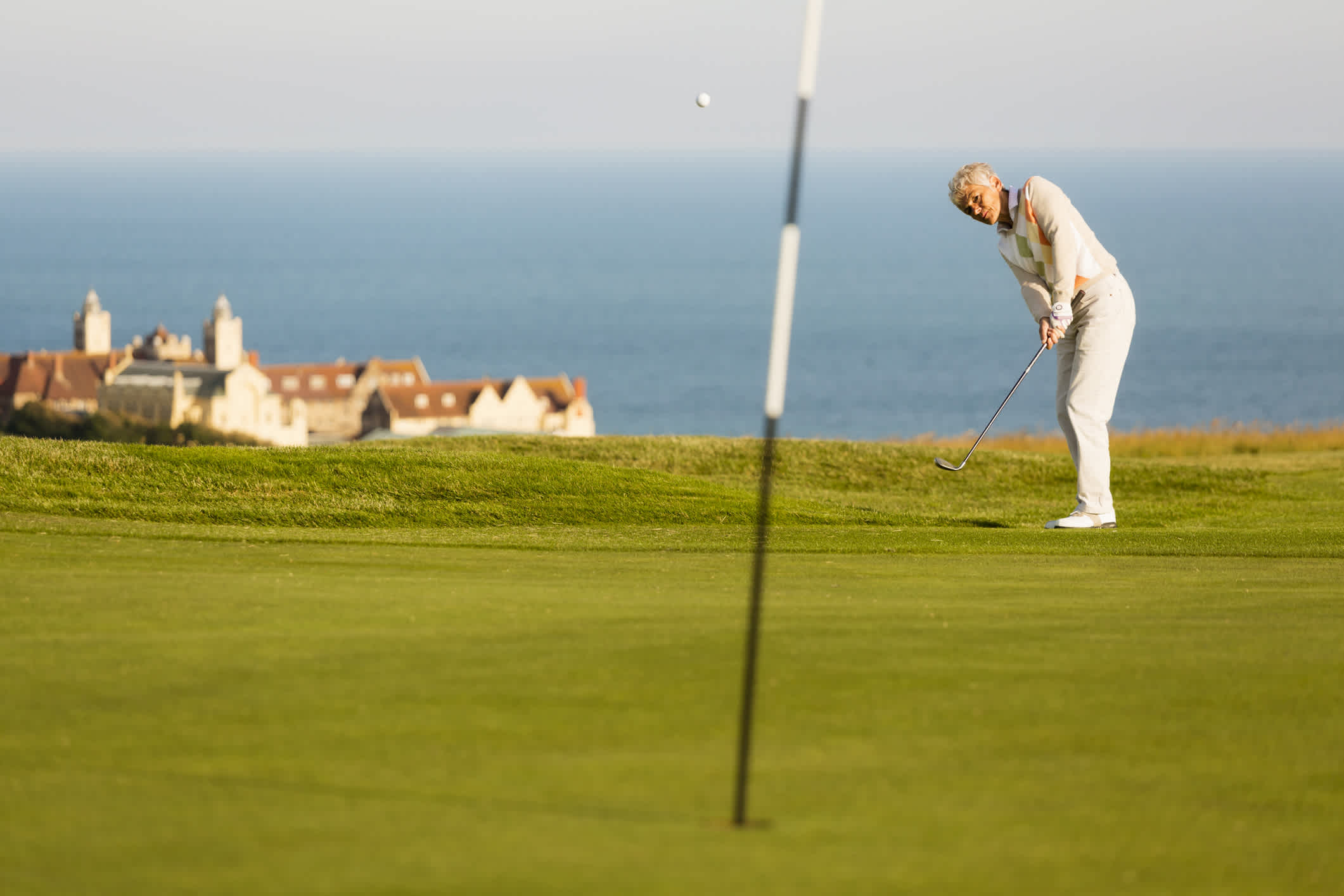 Ein Golfer schlägt den Ball auf einem englischen Golfplatz auf das Grün.

