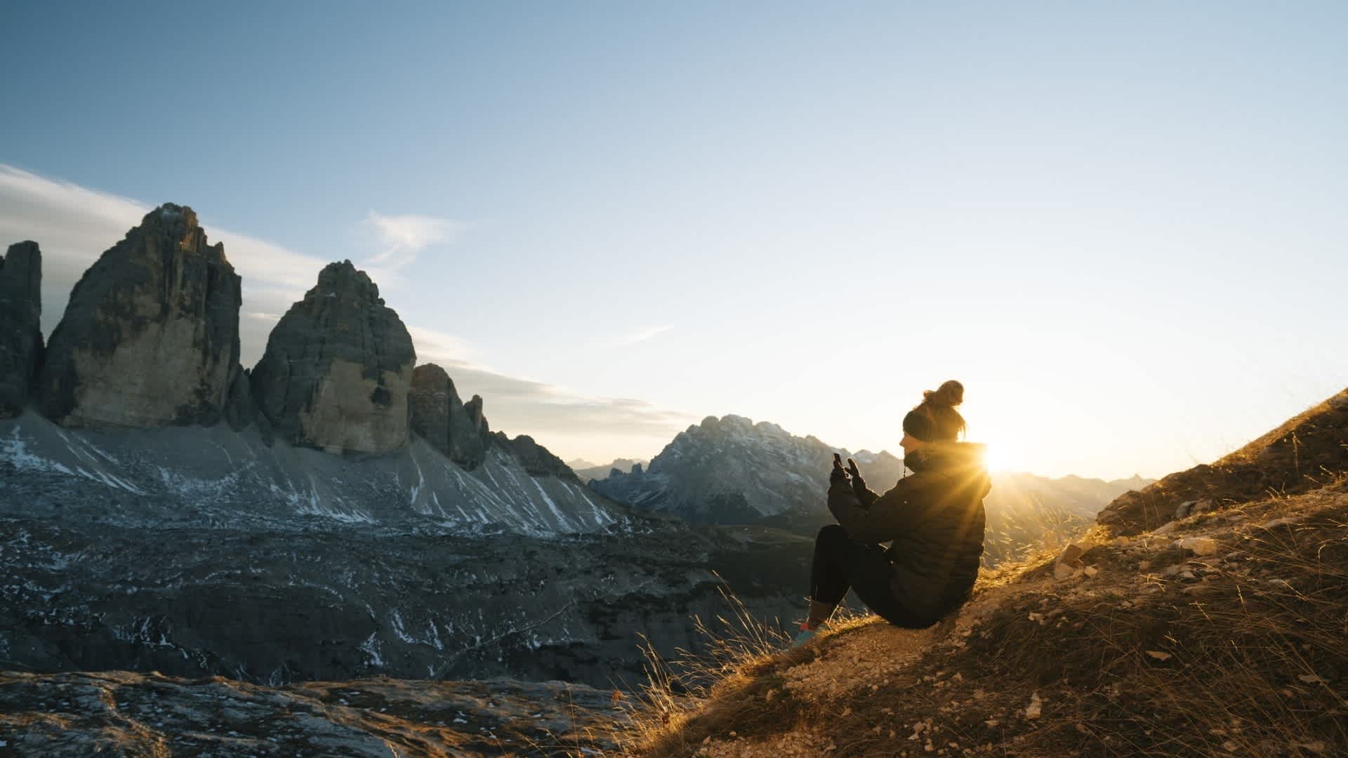 Frau, die den Sonnenuntergang auf Berggipfel beobachtet