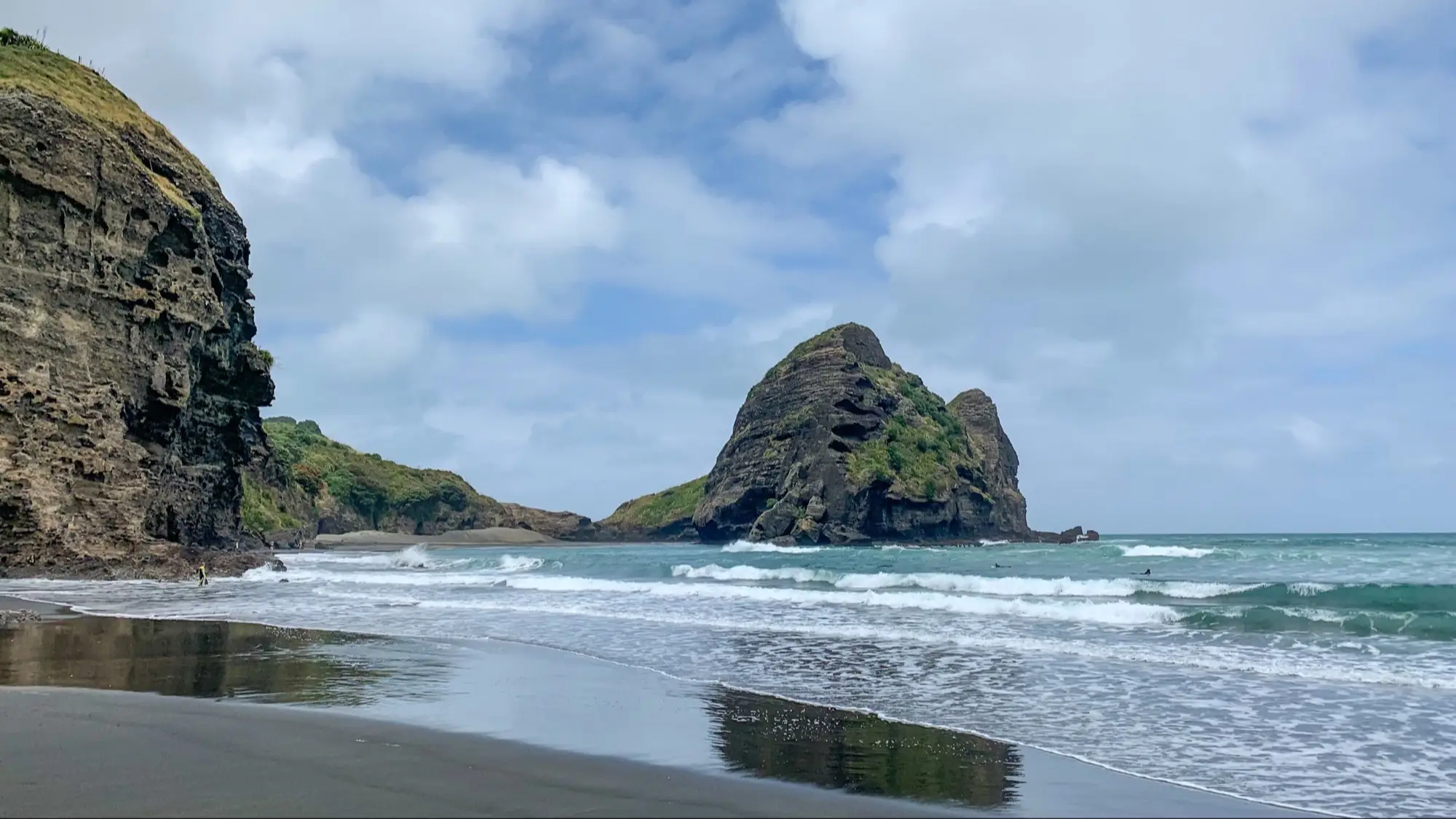 Neuseeland, Auckland, Piha Beach Der Strand Piha Beach in Auckland, Neuseeland mit Blick auf das Wasser und Felsen bei wolkigem Wetter.