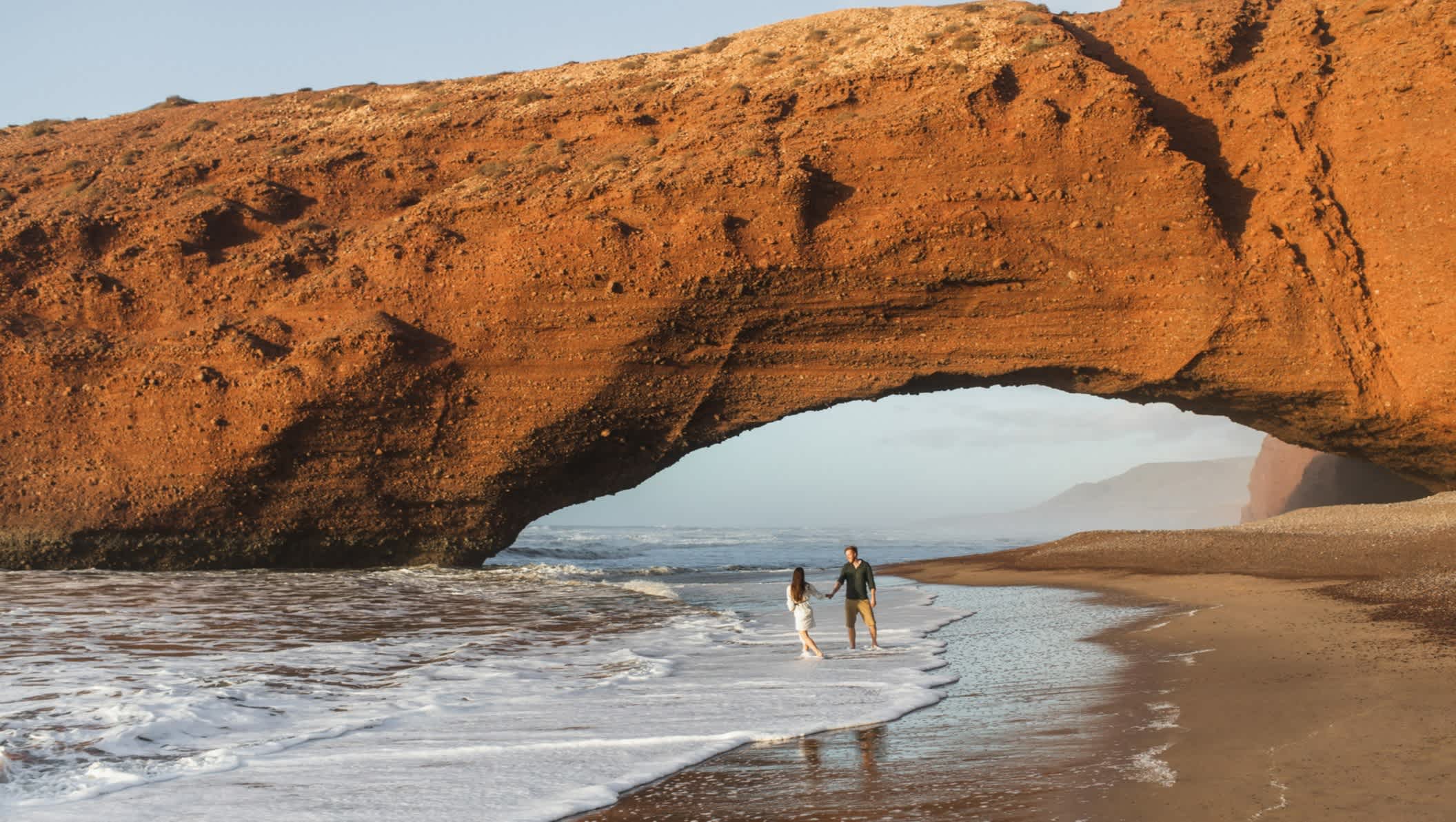 Couple se promenant sur la plage de Legzira, Maroc