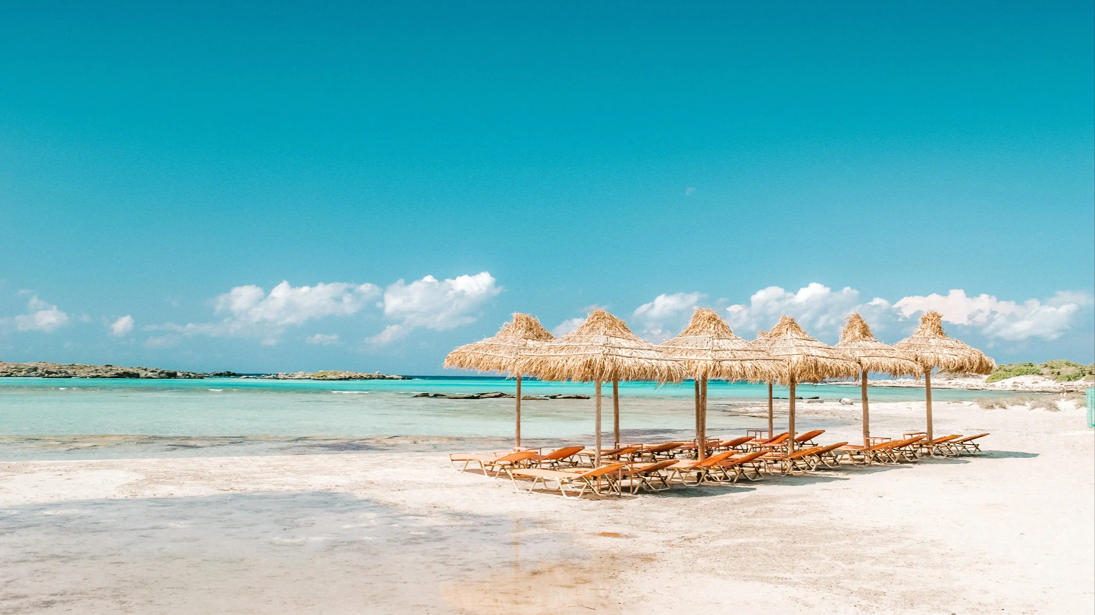 Griechenland, Kreta, Strand von Elafonissi Leere Sonnenliegen am Strand von Elafonissi auf der Insel Kreta, Griechenland mit Sonnenschirmen und Liegen mit Blick auf das Meer und den weißen Strand.