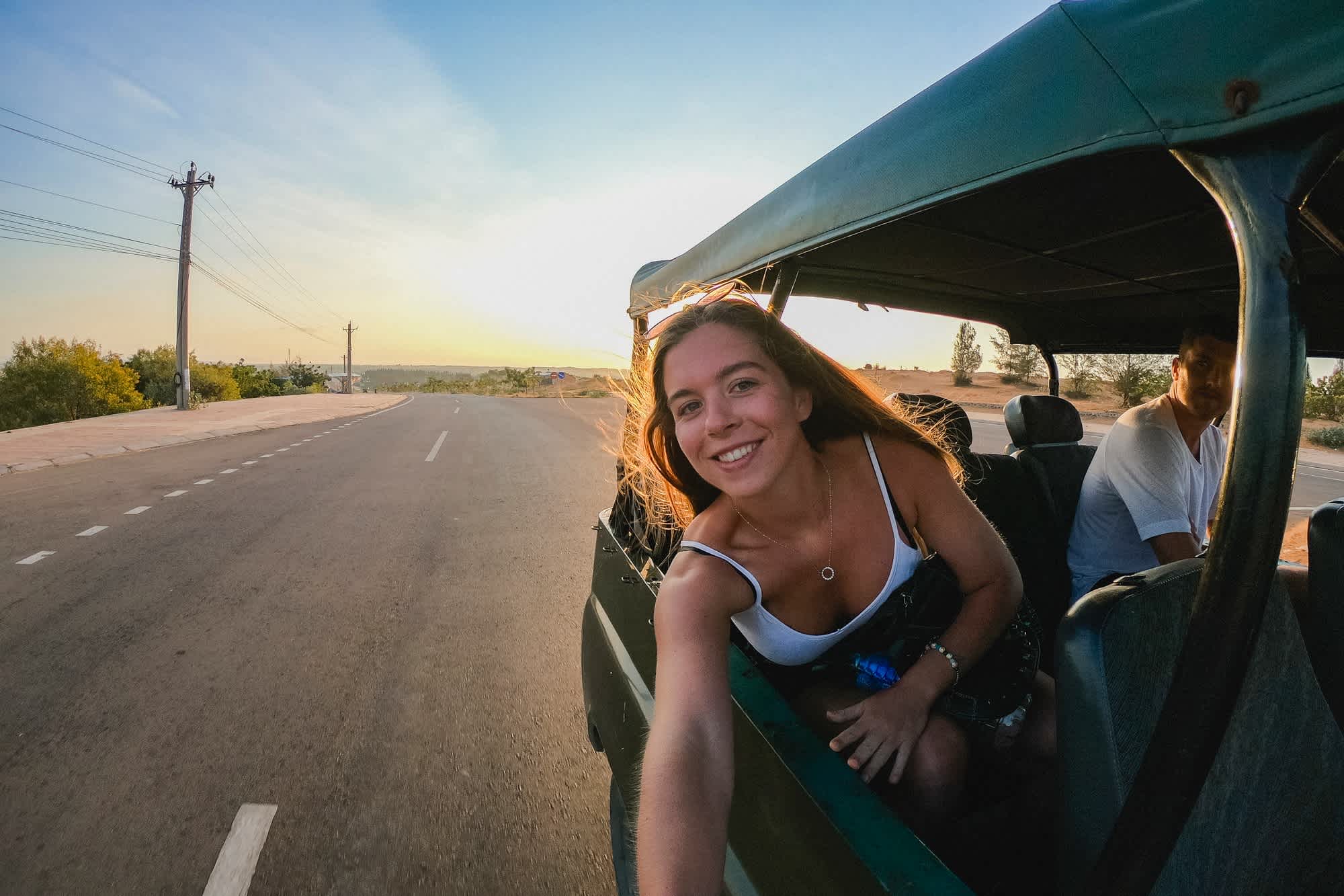 Ein Selfie eines jungen Paares auf dem Rücksitz eines fahrenden Fahrzeugs, während sie im Urlaub durch Vietnam fahren.
