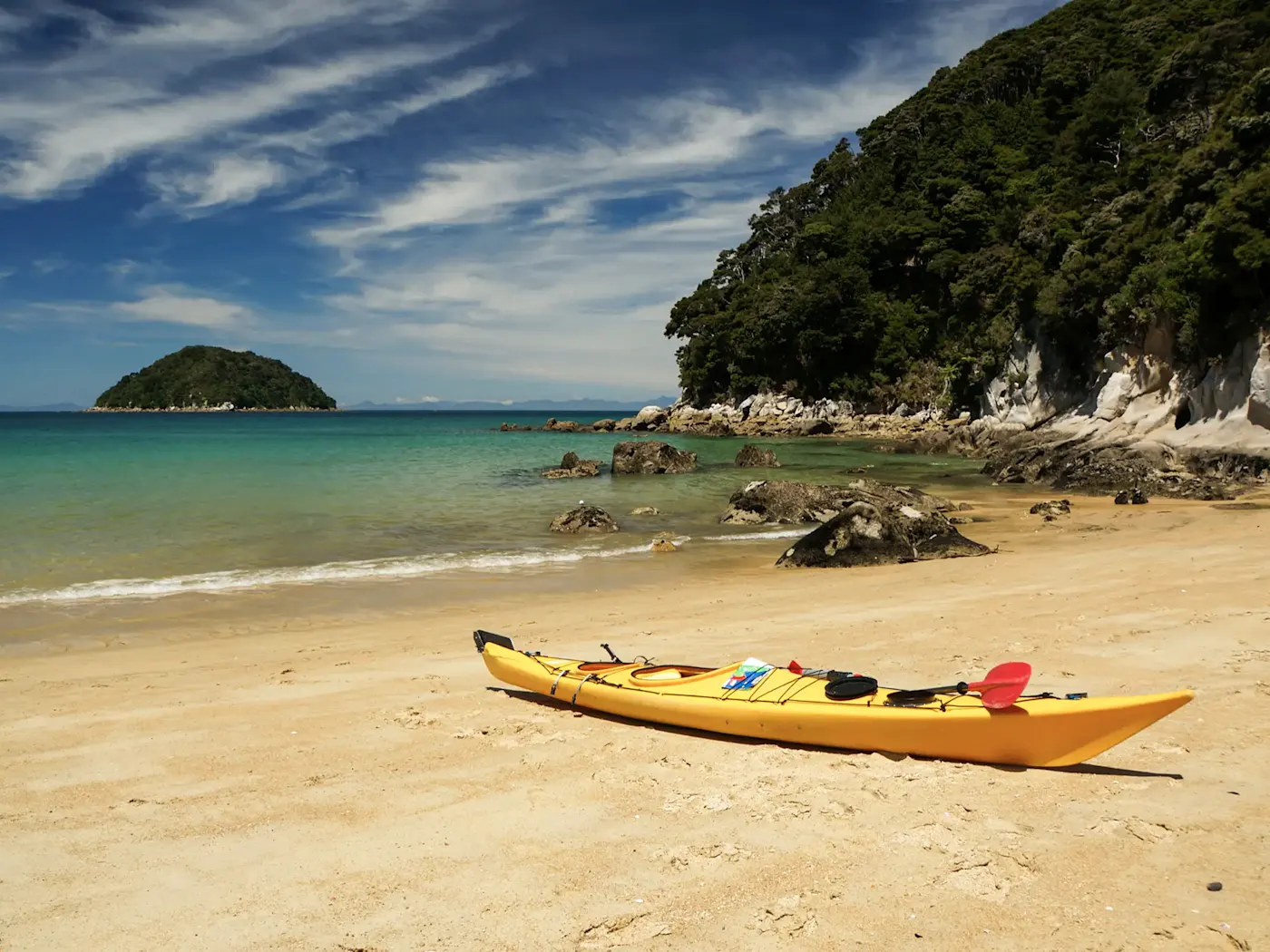 Neuseeland, Südinsel, Marahau, Abel-Tasman-Nationalpark Ein gelbes Kajak liegt an einem ruhigen Strand im Abel-Tasman-Nationalpark, Marahau, Südinsel, Neuseeland.