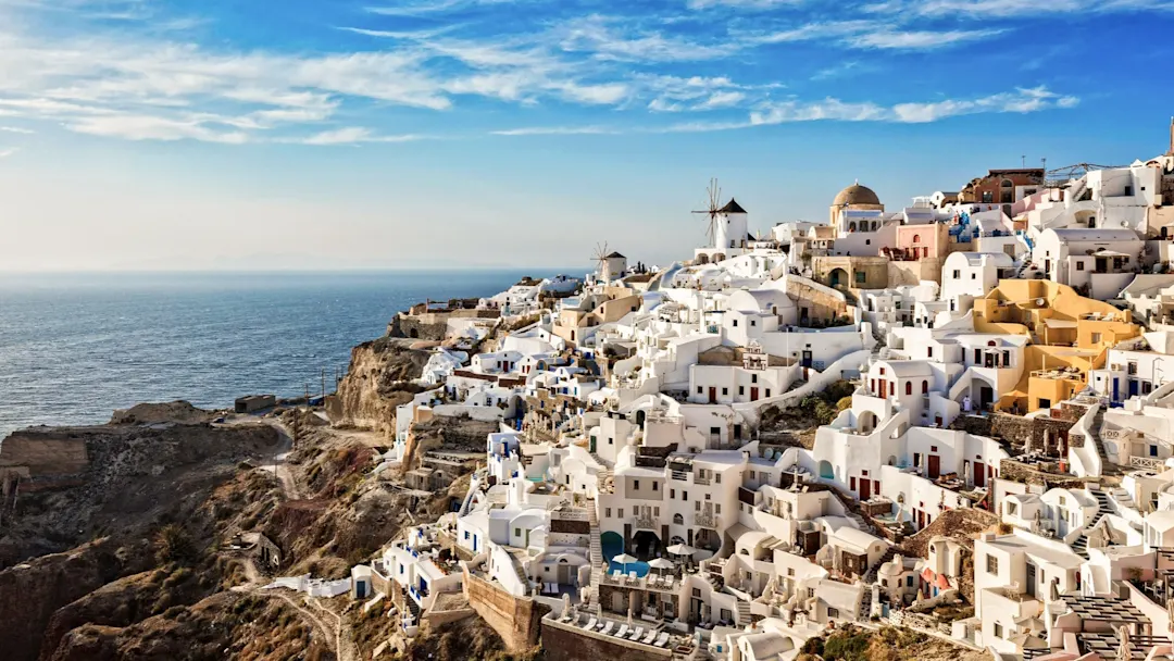 Weißes Dorf mit Windmühlen und Meerblick im Sonnenlicht. Oia, Santorini, Kykladen, Griechenland.