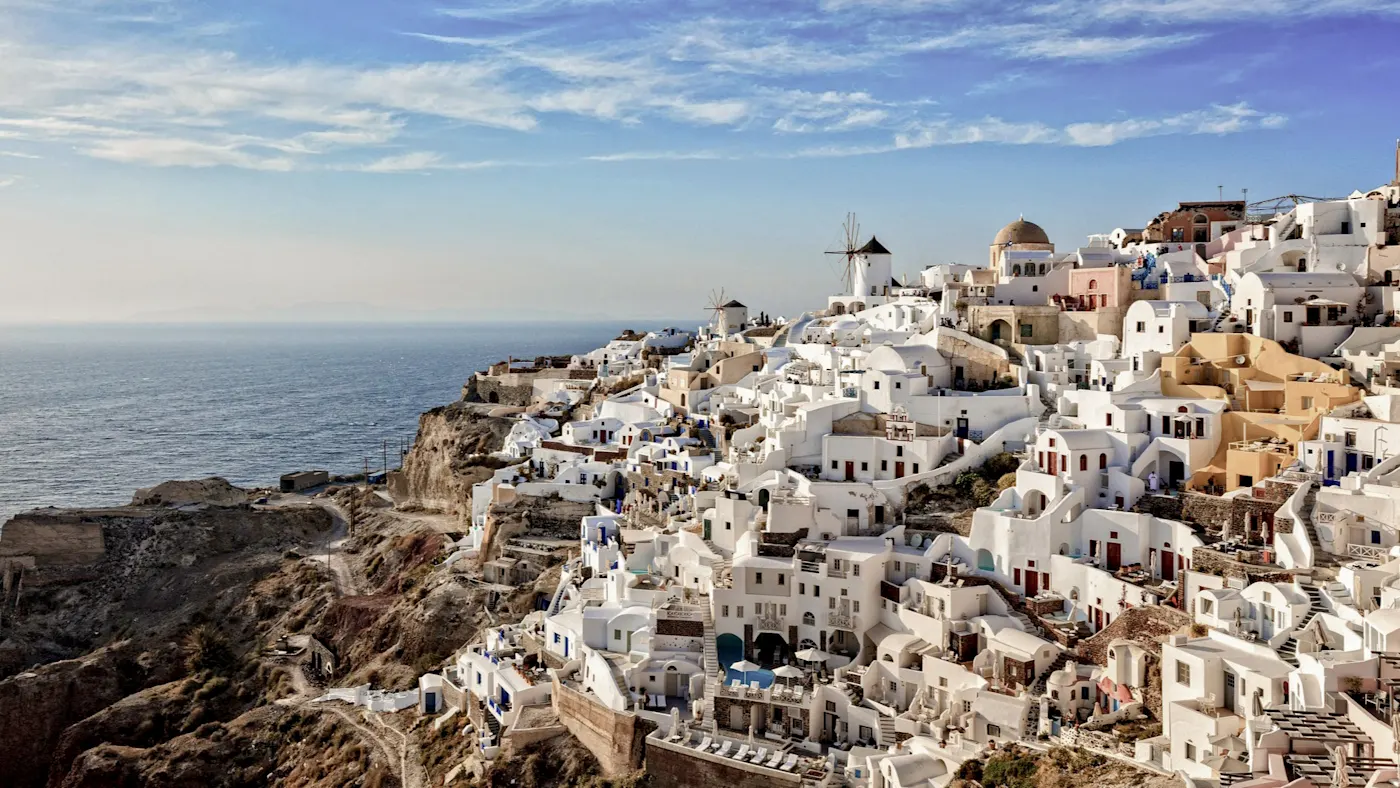 Weißes Dorf mit Windmühlen und Meerblick im Sonnenlicht. Oia, Santorini, Kykladen, Griechenland.