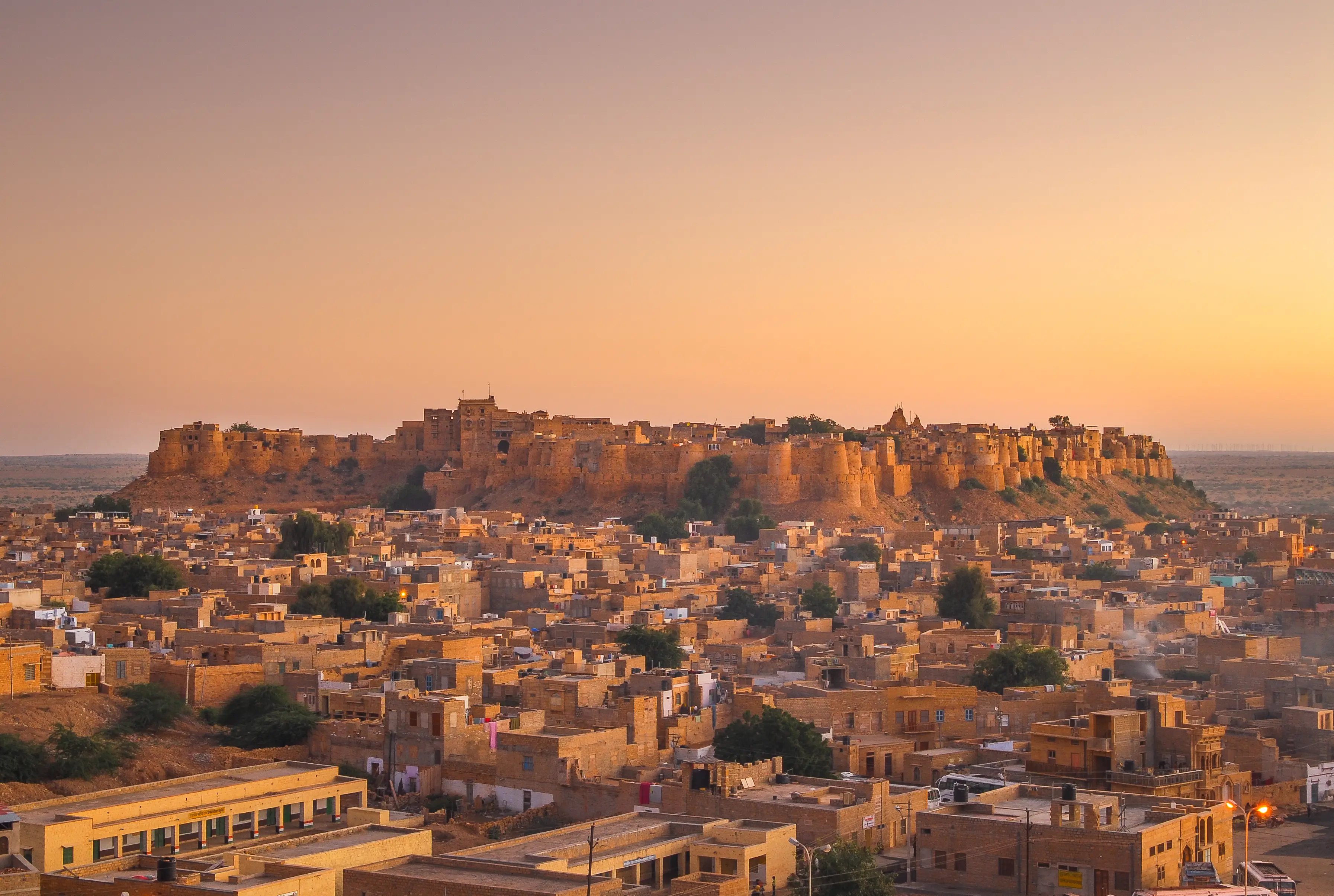 Jaisalmer Fort bei Sonnenuntergang, goldene Festung thront über der Wüstenstadt mit sandfarbenen Gebäuden in Rajasthan.