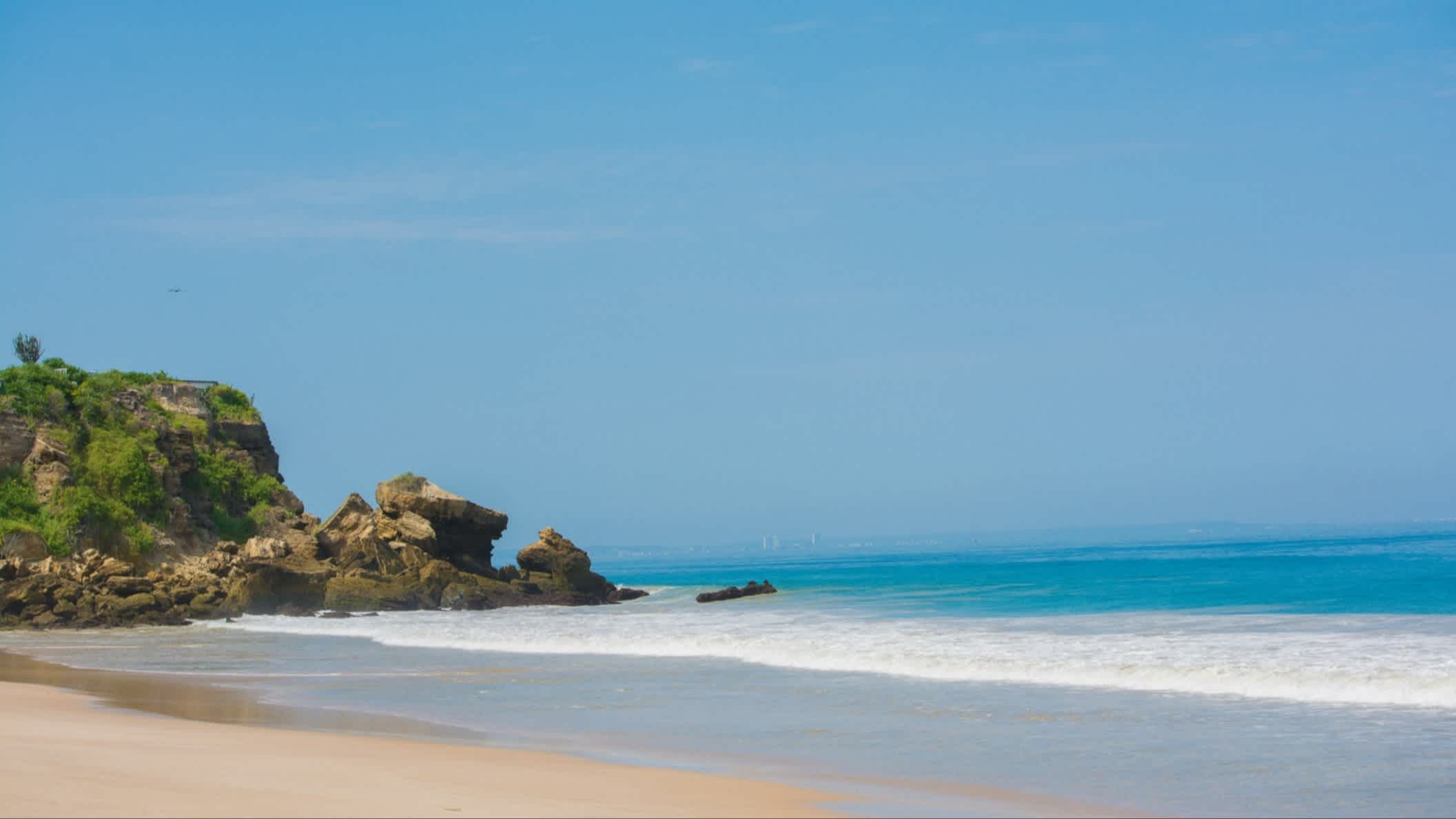 Der Strand von Ayangue, Provinz Santa Elena, Ecuador bei Sonnenschein mit Blick auf Felsen und das blaue ruhige Wasser.