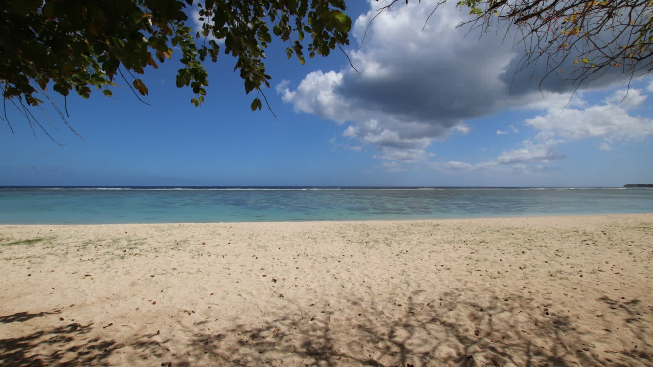Schattiger Sandstrand von St. Felix Beach, Süden, Mauritius bei sonnigem Wetter und mit Blick auf das Wasser und durch Vegetation.