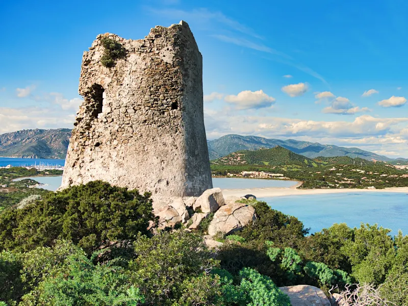 Italien, Sardinien, Villasimius Vieille tour en pierre avec vue sur une baie et des montagnes. Villasimius, Sardaigne, Italie.