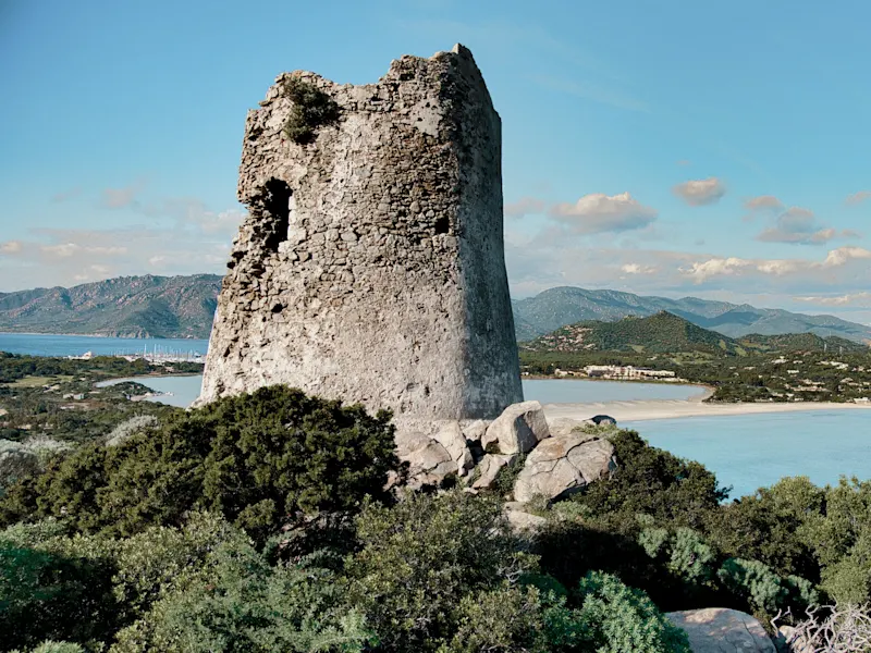 Alte Steinturmruine mit Blick auf eine Bucht und Berge. Villasimius, Sardinien, Italien.
