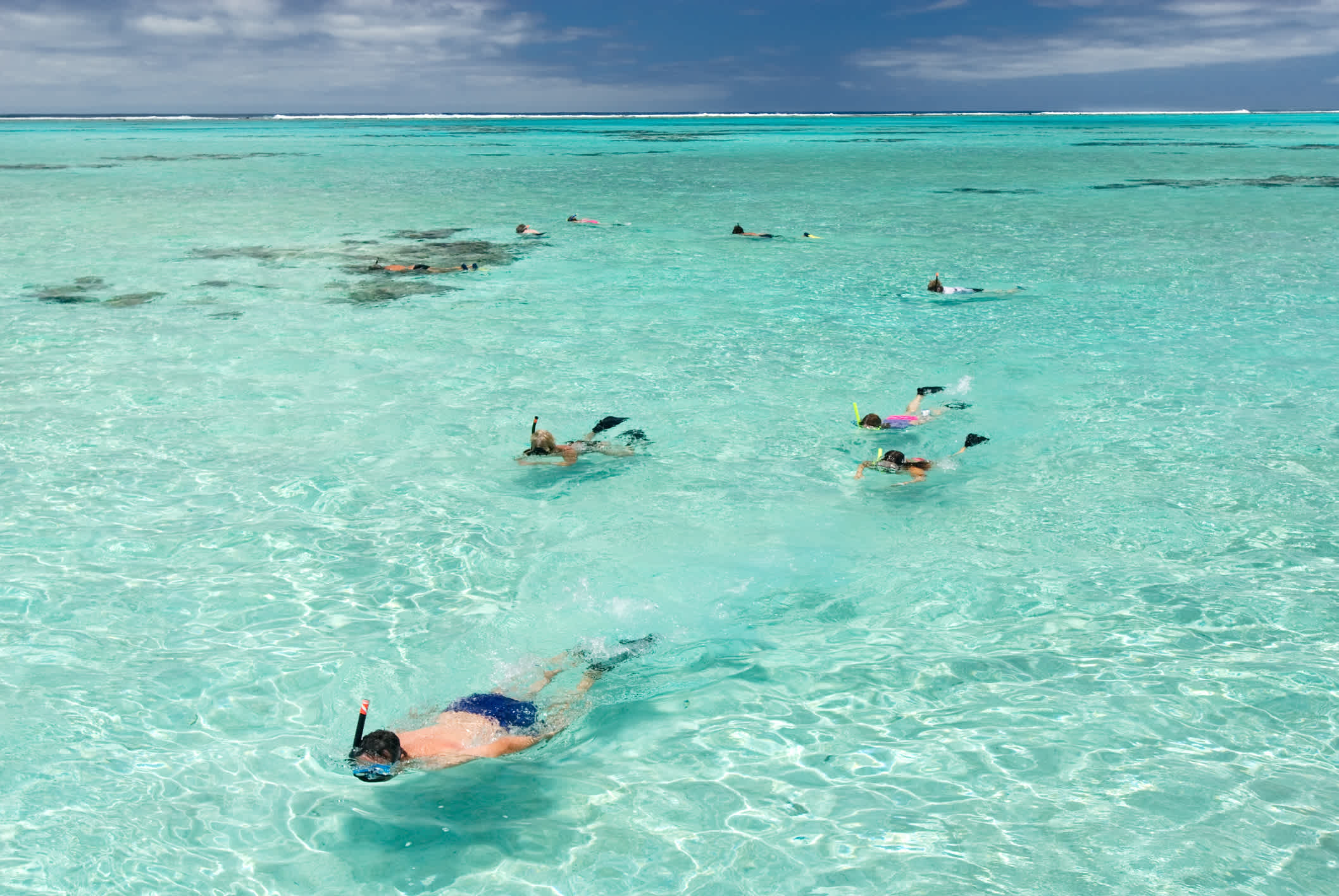 Eine Gruppe von Schnorchlern, die das kristallklare Wasser und die Korallenriffe der Aitutaki-Lagune auf den Cookinseln genießen