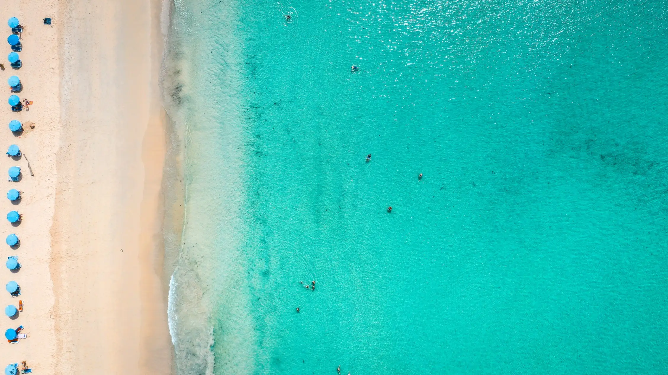 Thailand, Phuket, Kata Noi Beach Luftaufnahme des Kata Noi Beach auf Phuket mit türkisblauem Wasser, Sandstrand und blauen Sonnenschirmen.