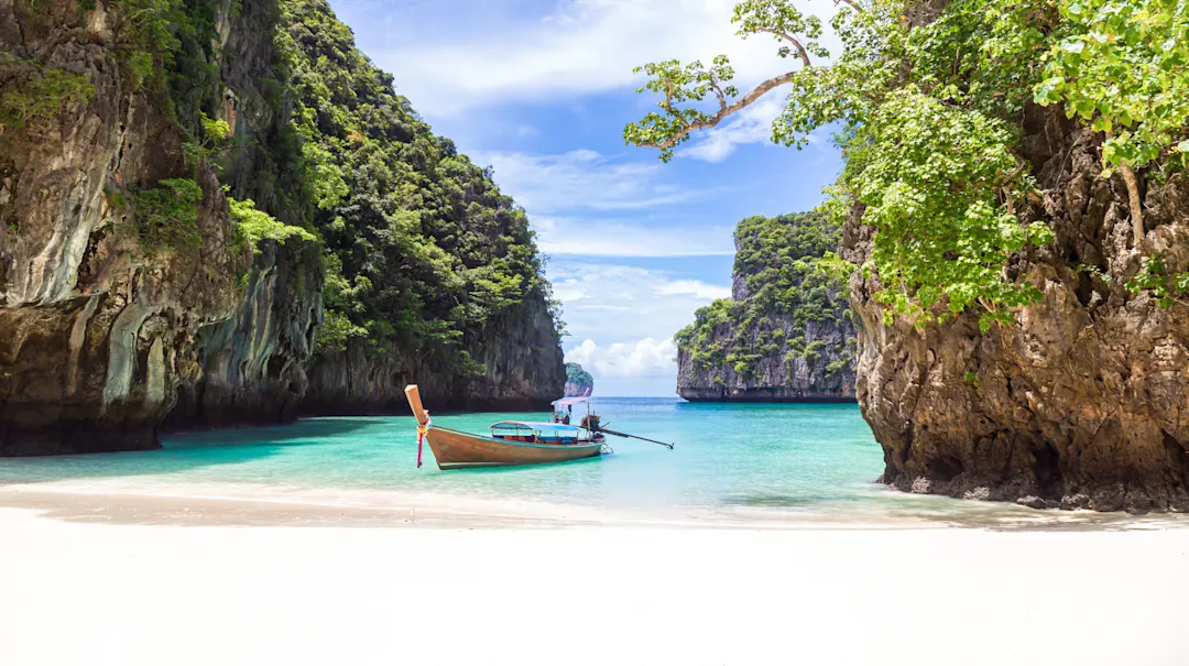 Das traditionelle thailändische hölzerne Longtail-Boot und der wunderschöne Strand in der Provinz Phuket, Thailand.

