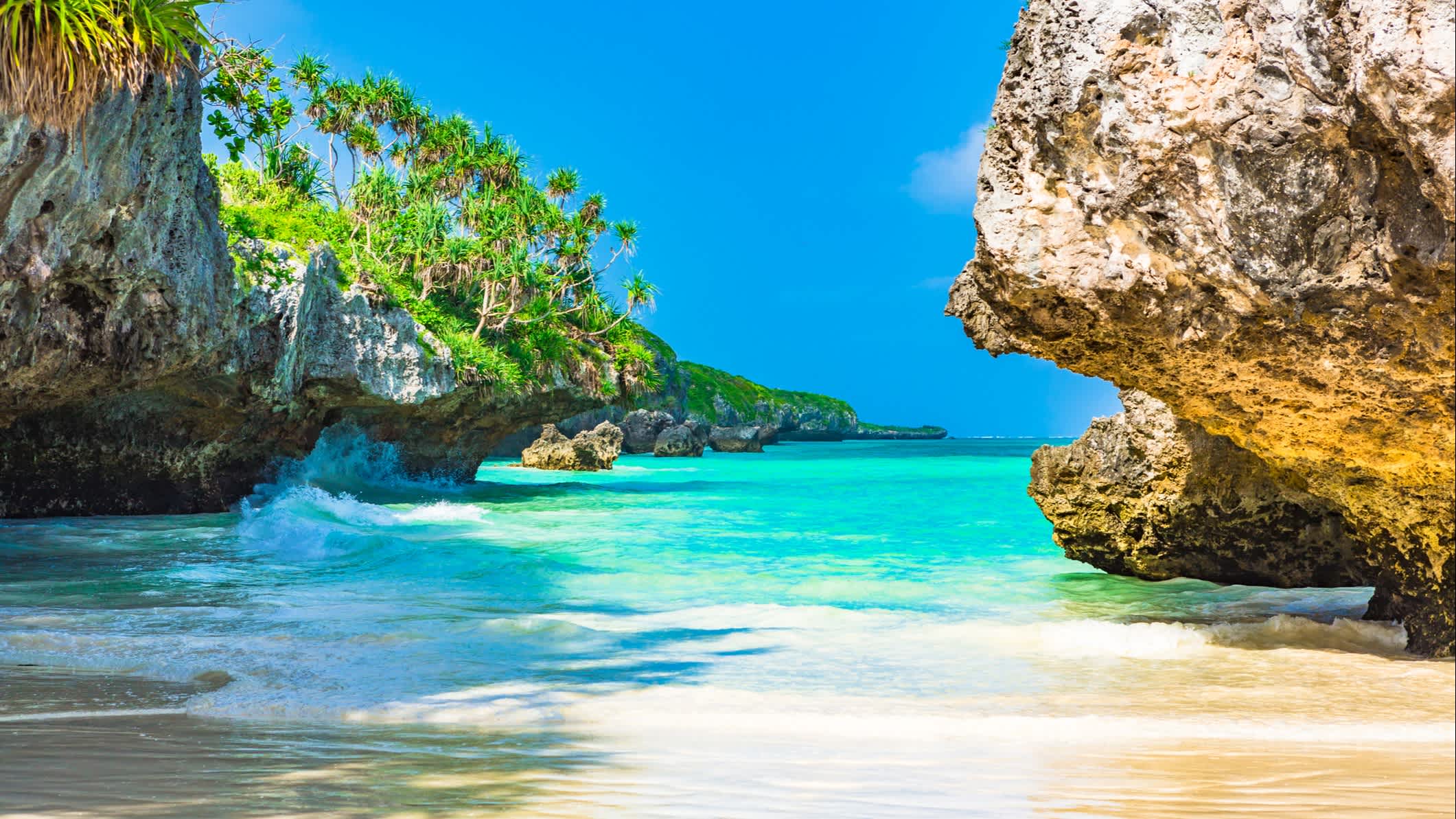 Sandstrand auf Sansibar mit Felsformationen und türkisblauem Meer.