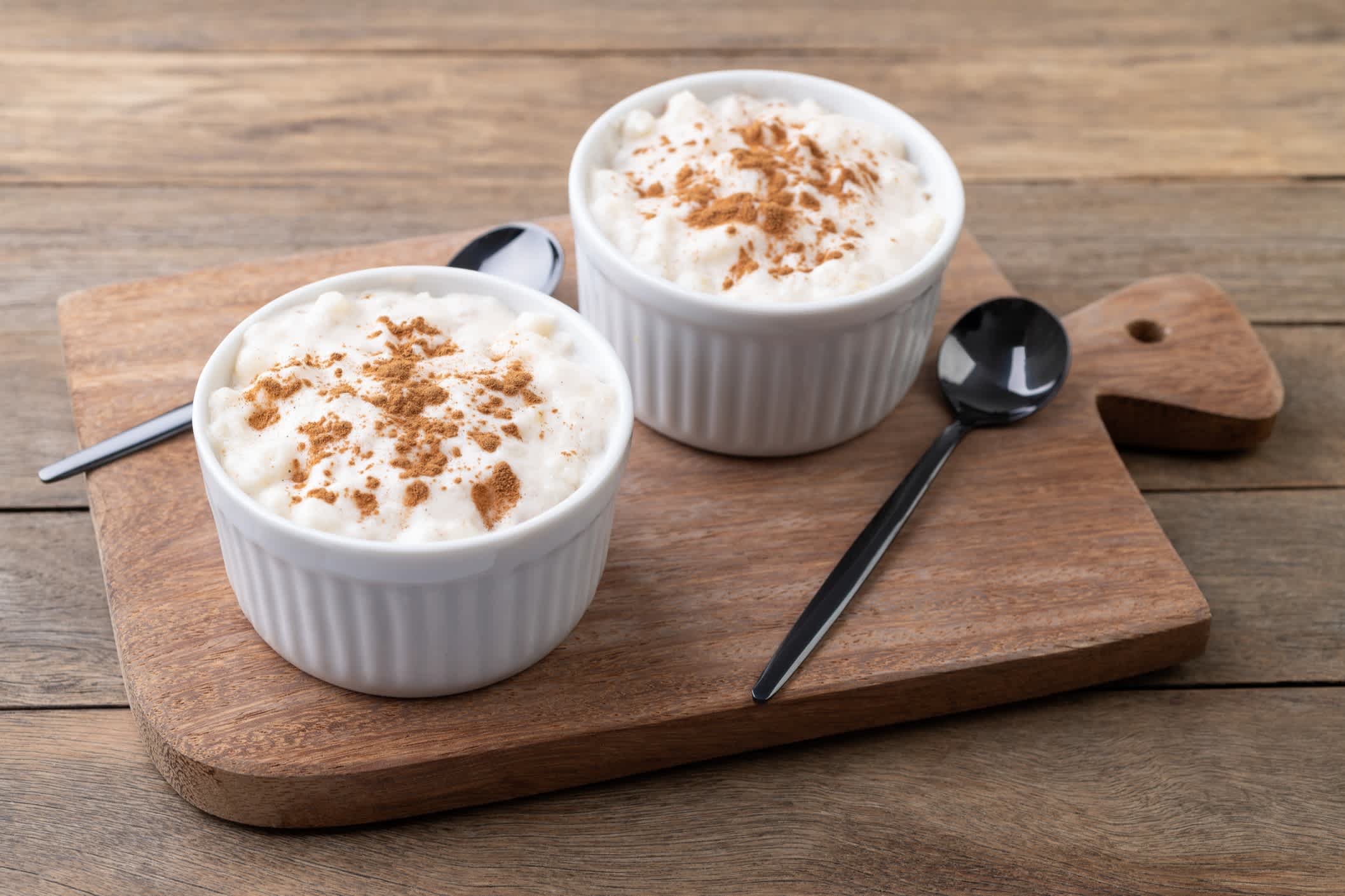 Canjica oder Munguza, typisch brasilianische weiße Mais-Süßcreme mit Zimt über Holztisch
