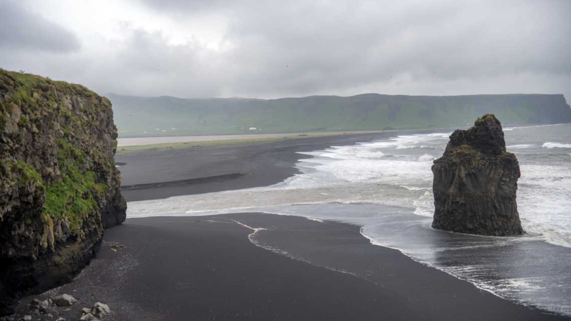 Der schwarze Sandstrand von Reynisfjara und der Berg Reynisfjall von der Landzunge Dyrholaey an der Südküste Islands