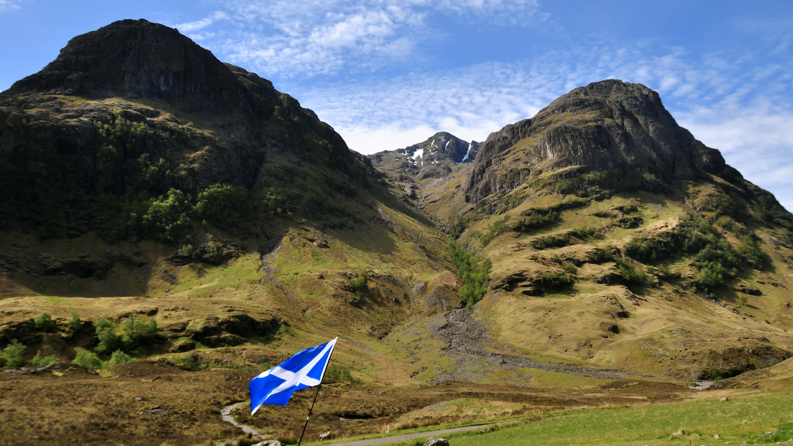 Eine Drei-Schwestern-Bergkette in Glencoe mit einer schottischen Flagge im Vordergrund, Schottland
