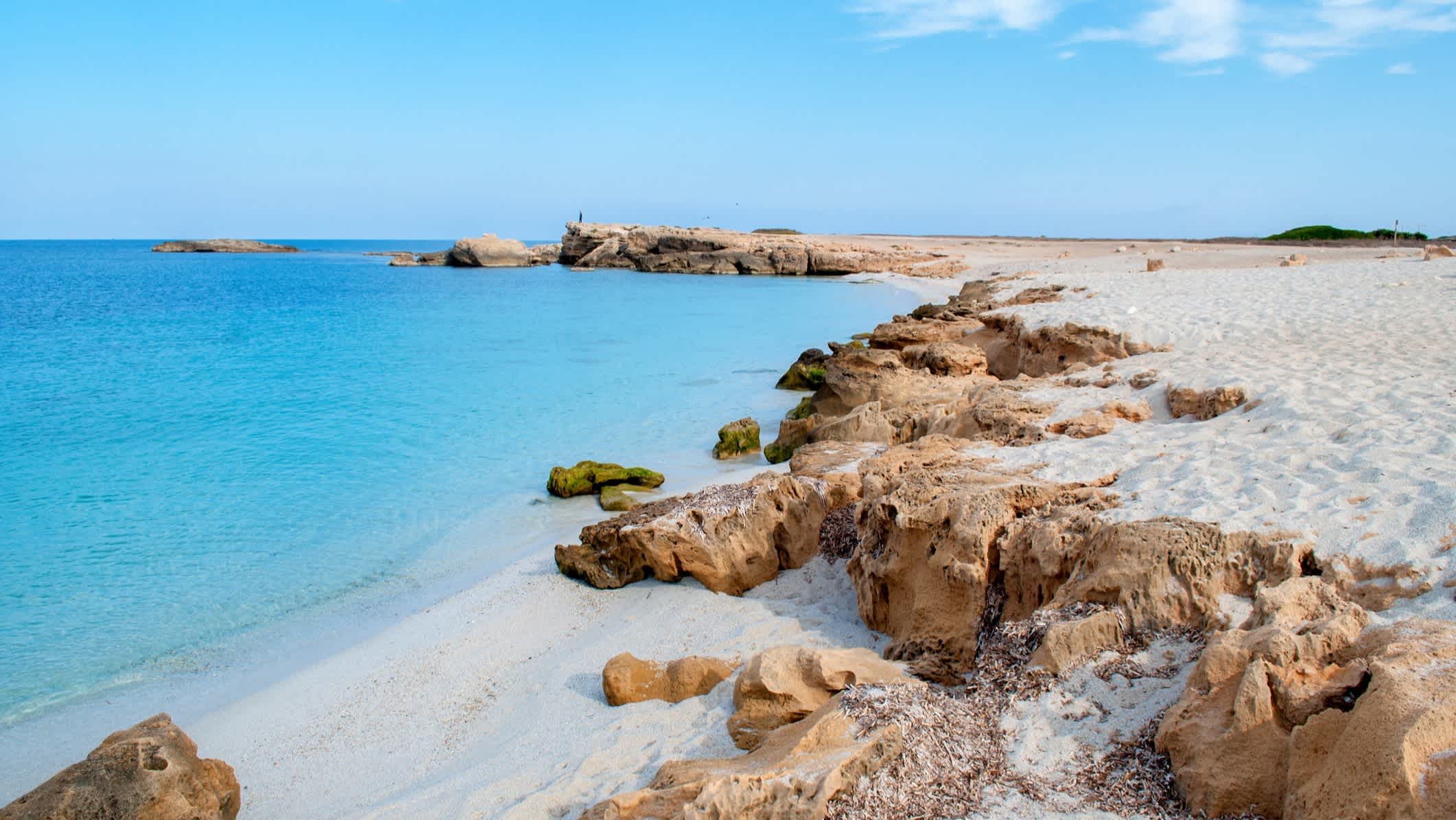 Blick zum leeren Strand Is Arutas in Sardinien, Italien mit Felsen im Bild sowie bei Sonnenschein.