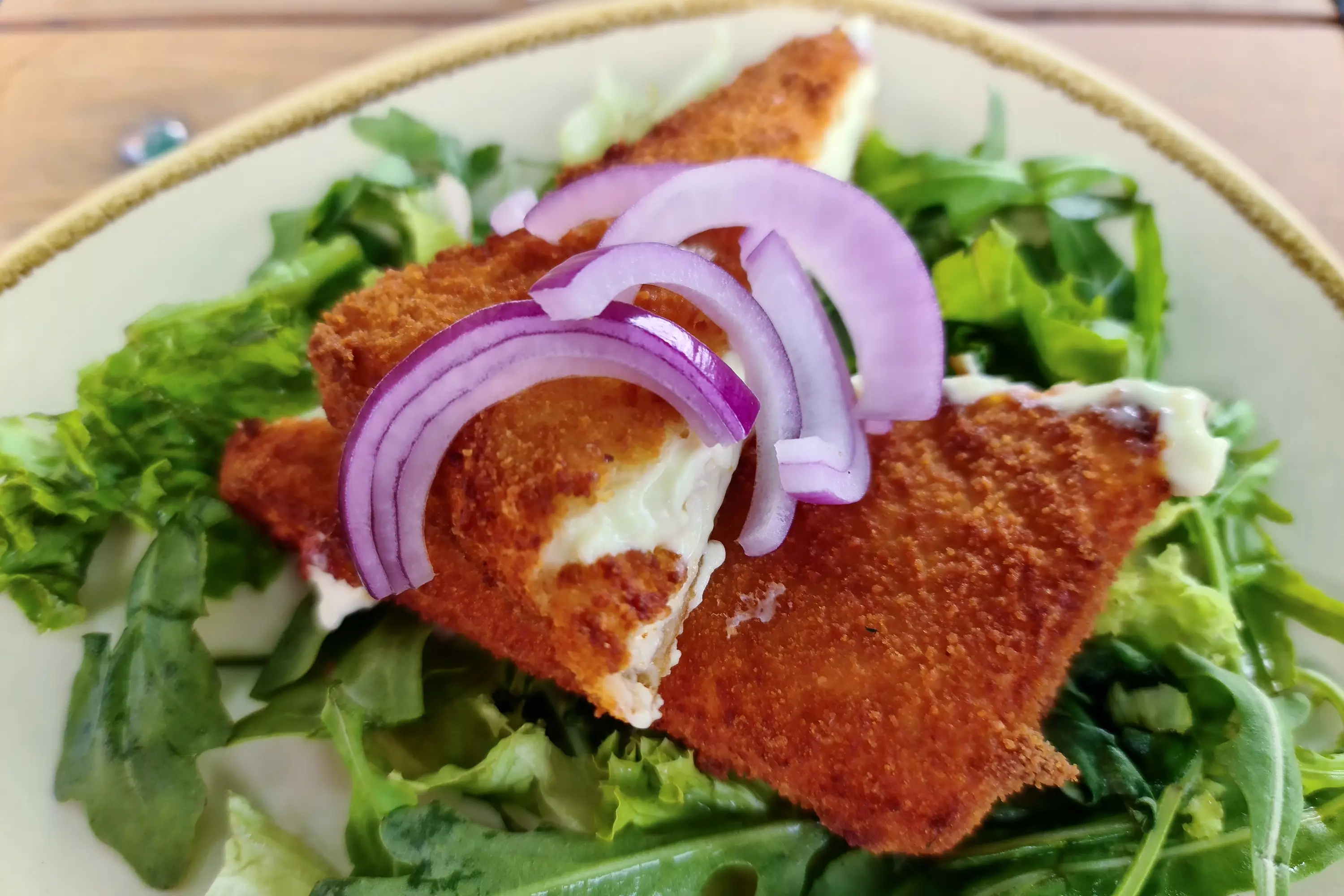 Fromage Saganaki frit sur une assiette de salade verte.