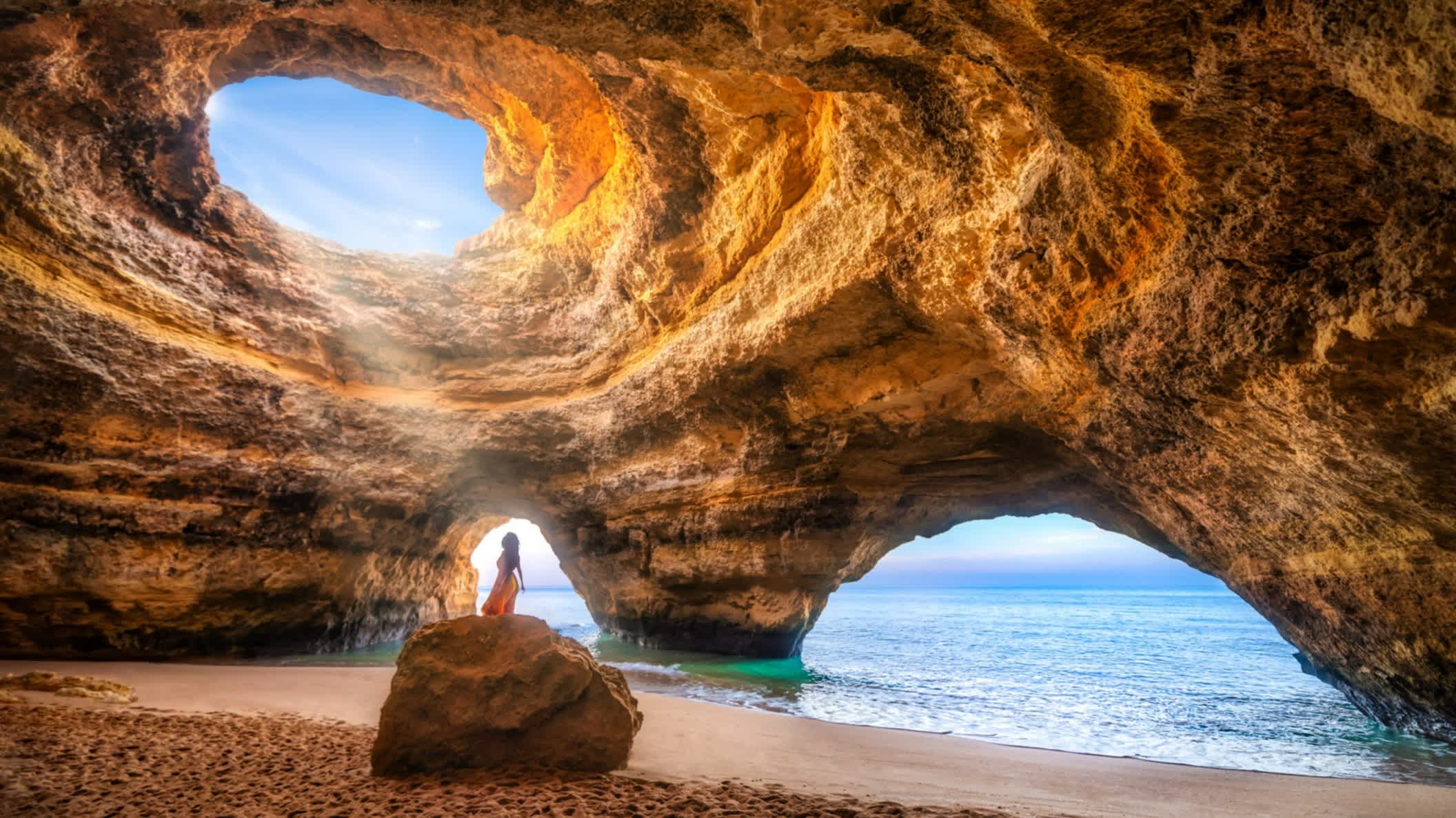 Frau unter dem Sonnenlicht in der natürlichen Meereshöhle von Benagil, Algarve, Portugal