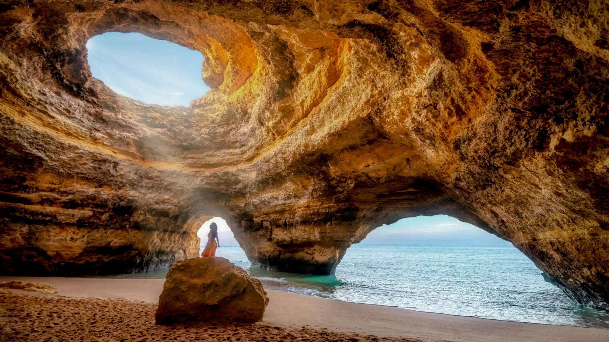 Frau unter dem Sonnenlicht in der natürlichen Meereshöhle von Benagil, Algarve, Portugal