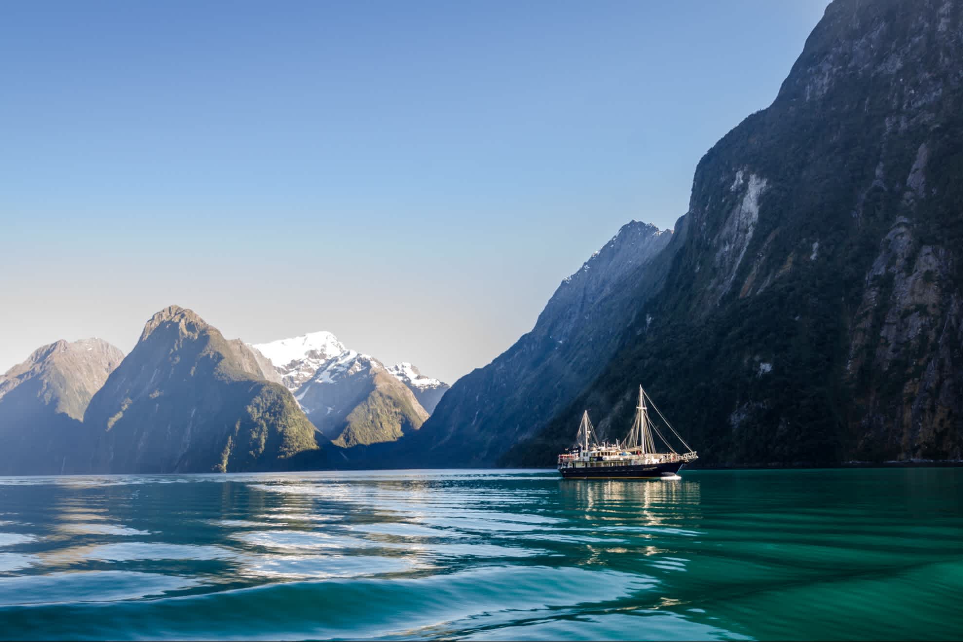Milford Sound avec un bateau de croisière au lever du soleil, Nouvelle-Zélande.