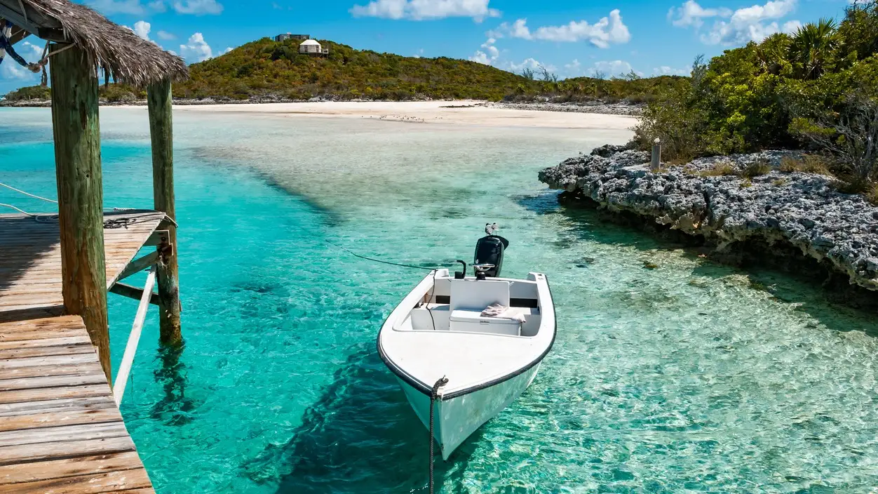 Ein kleines Außenbord-Motorboot legte an einem Holzpier im tropischen Paradies der Exuma-Inseln der Bahamas an.

