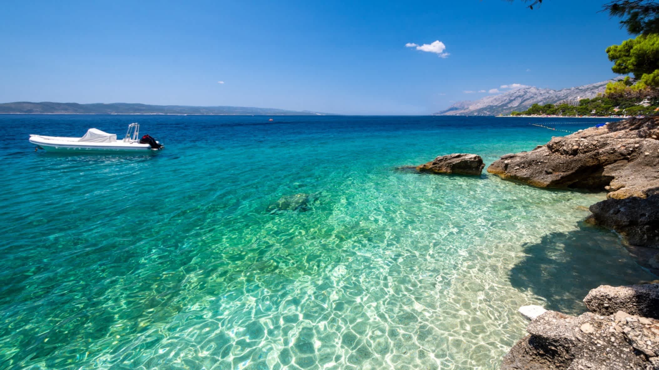 Der Strand und ein Boot am Ufer an der Makarska Riviera, Kroatien bei strahlendem Himmel.