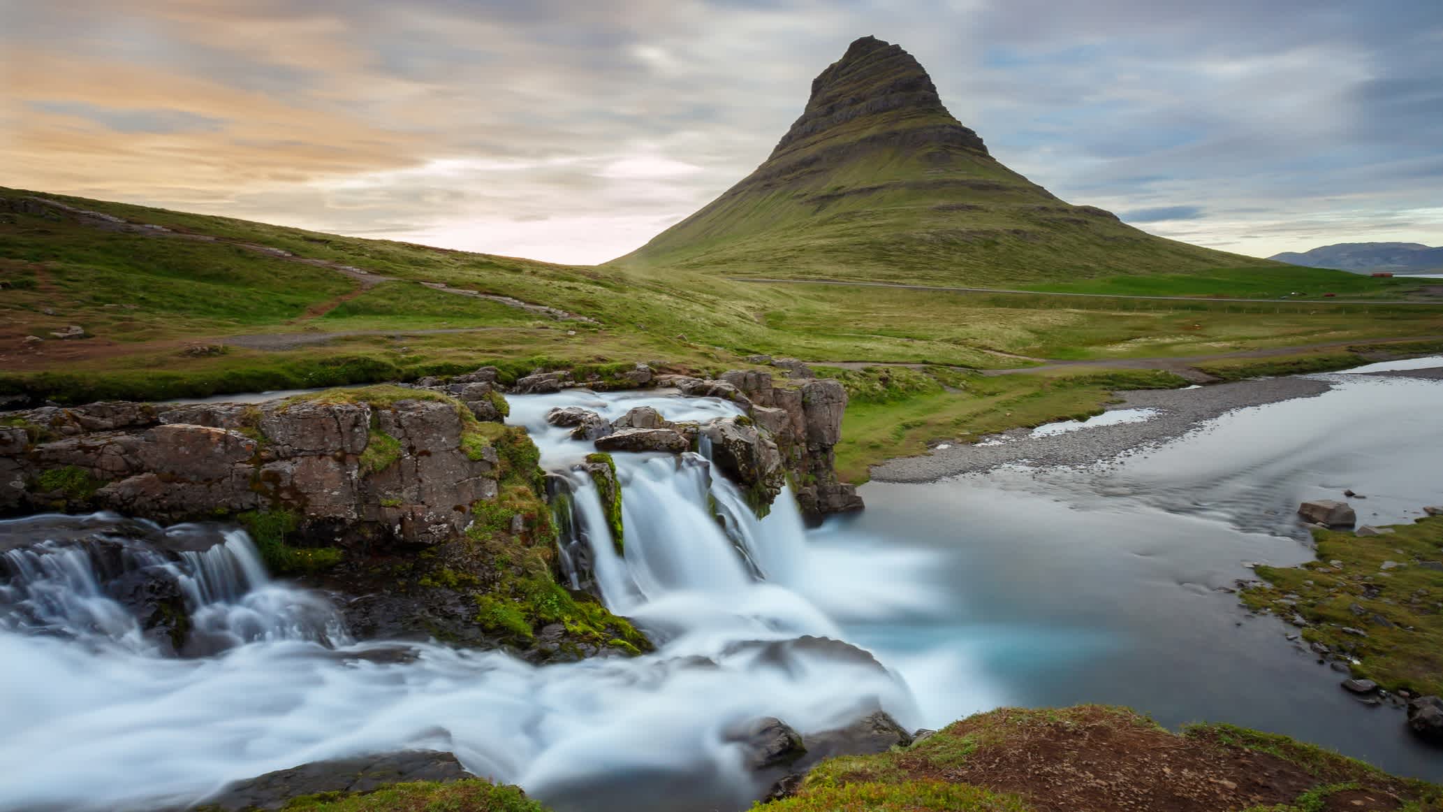 Der Sonnenuntergang beim Kirkjufellsfoss-Wasserfall mit dem Kirkjufell-Berg im Hintergrund, Halbinsel Snaefellsnes, Island.

