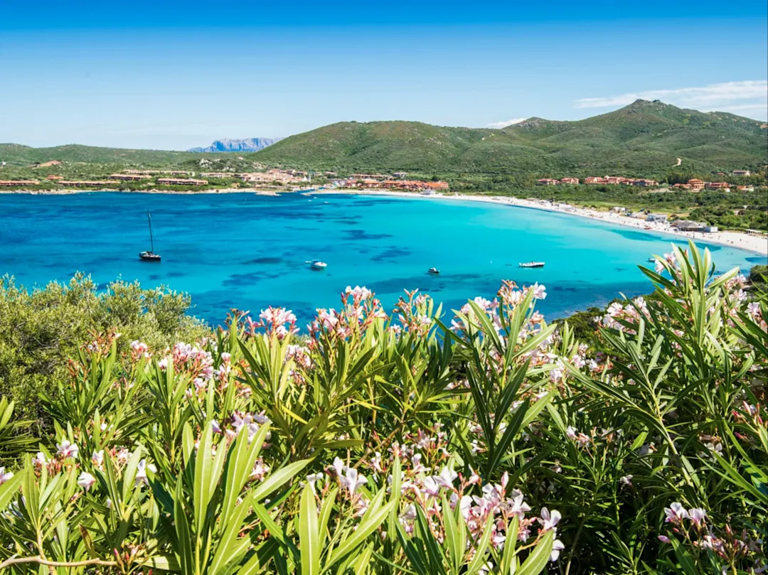 Der Blick zum Golf von Marinella bei Olbia in Sardinien bietet eine atemberaubende Aussicht auf das türkisblaue Wasser, das sanft an die Felsen und weißen Sandstrände plätschert