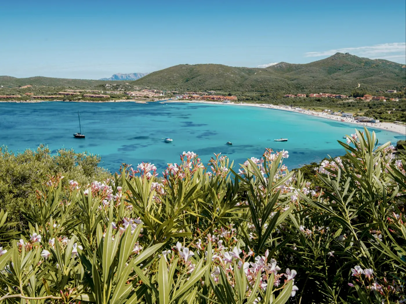 Der Blick zum Golf von Marinella bei Olbia in Sardinien bietet eine atemberaubende Aussicht auf das türkisblaue Wasser, das sanft an die Felsen und weißen Sandstrände plätschert