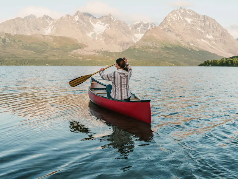 Personne pagayant dans un canoë rouge sur un lac calme. Tromsø, Troms, Norvège.