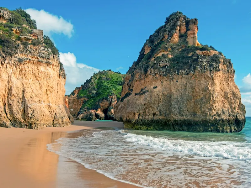 Strände, Portugals Küste An Portugals Küste ragen beeindruckende Felsenformationen und Klippen aus dem Meer, wie zum Beispiel an der Praia da Rocha, wo hohe, majestätische Klippen in den Himmel ragen und den Strand umrahmen