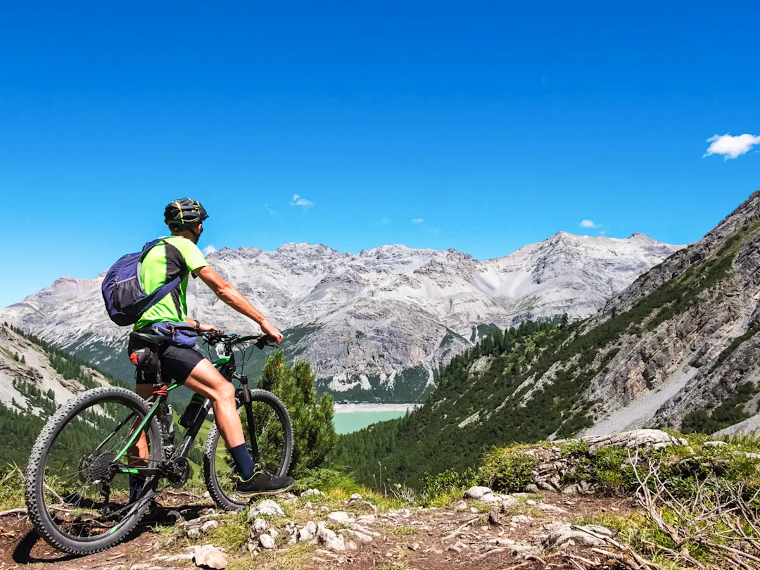 Ein Mountainbiker genießt den atemberaubenden Ausblick auf die Alpen, Livigno, Lombardei, Italien.