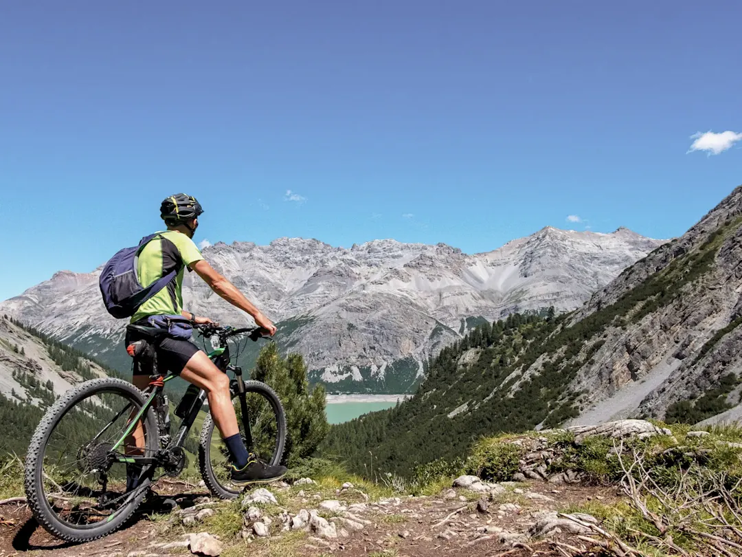 Ein Mountainbiker genießt den atemberaubenden Ausblick auf die Alpen, Livigno, Lombardei, Italien.