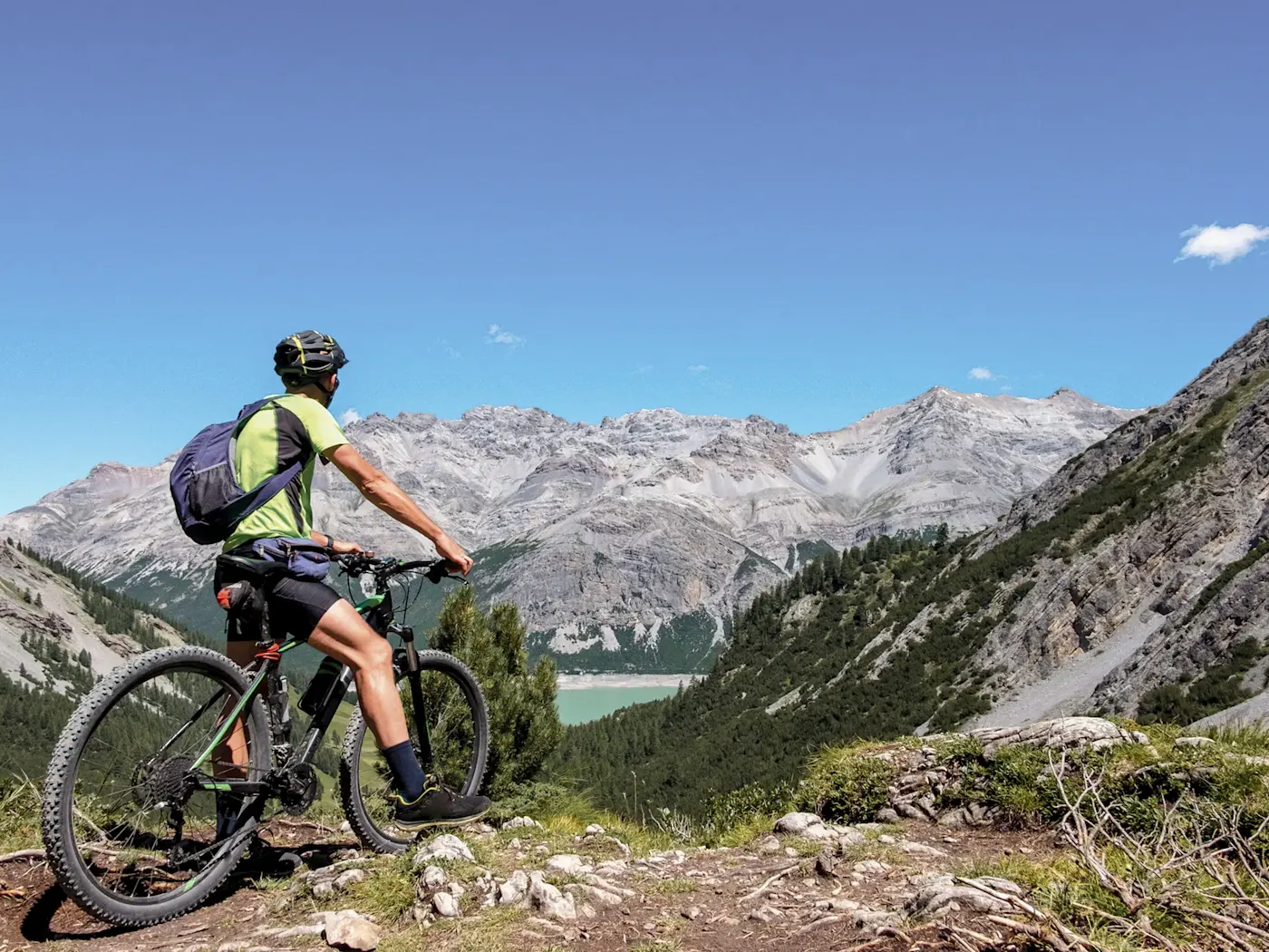 A mountain biker enjoys the breathtaking view of the Alps, Livigno, Lombardy, Italy.