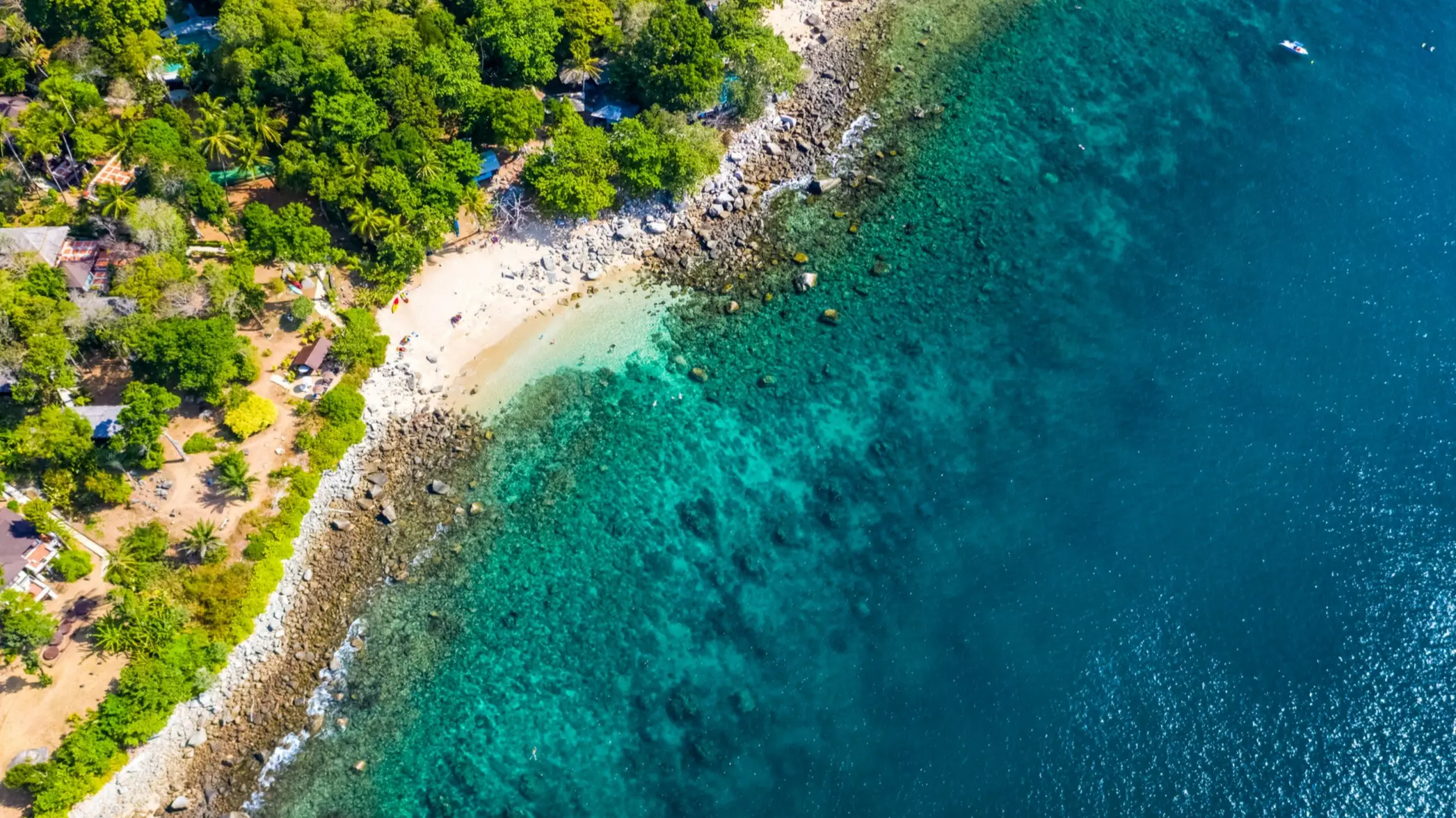 Thailand, Phuket, Ao Sane Beach Luftaufnahme des Ao Sane Beach auf Phuket, mit cyanblauem Wasser, Felsenküste und üppig grüner Vegetation.