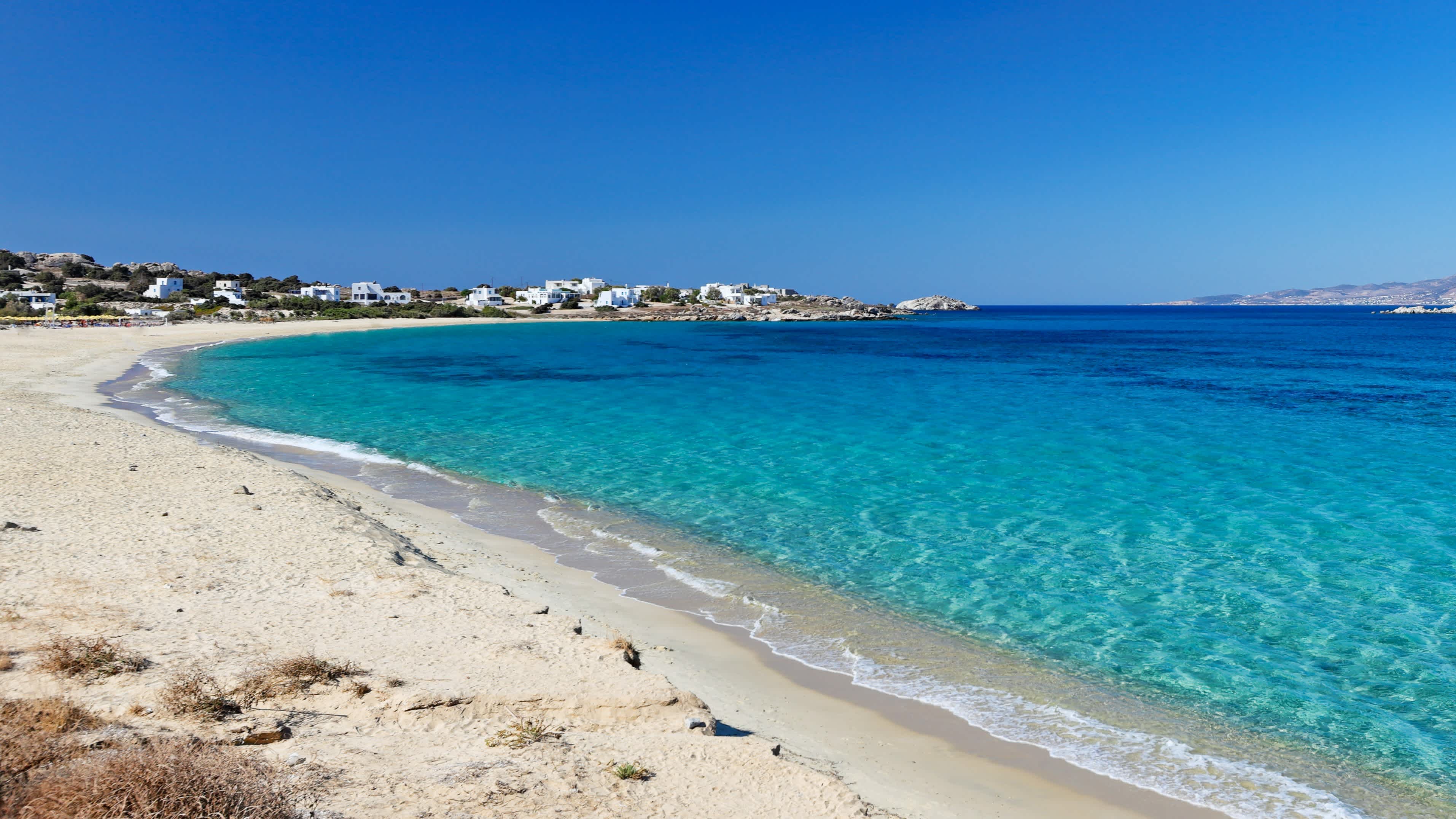 Strand des Limanaki Bay auf Naxos, Griechenland, mit weißem Sand und türkisblauem Meer.