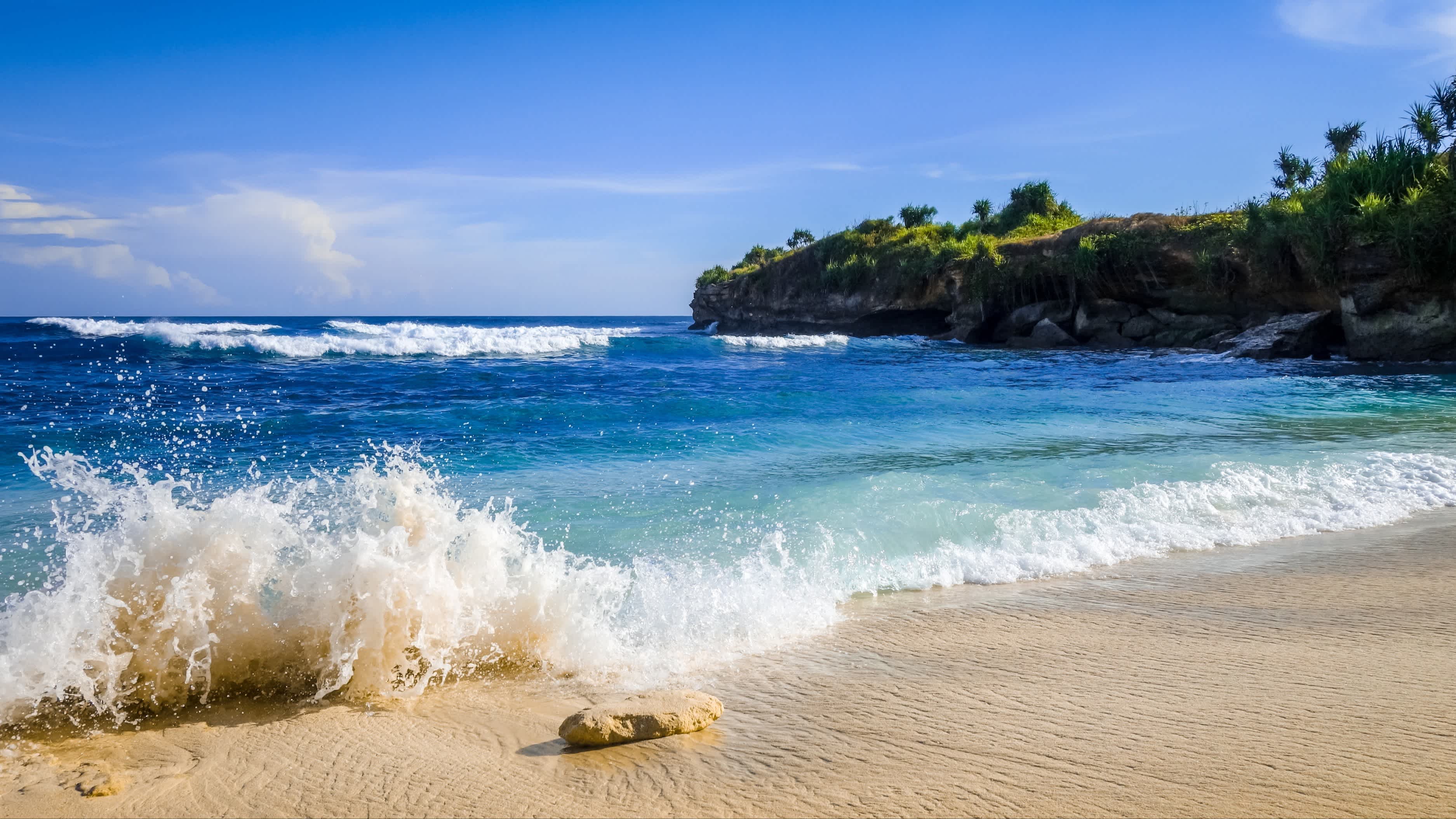 Aufnahme des Dream Beach auf Nusa Lembongan, Indonesien mit Wellen und grüner Küste im Bild.