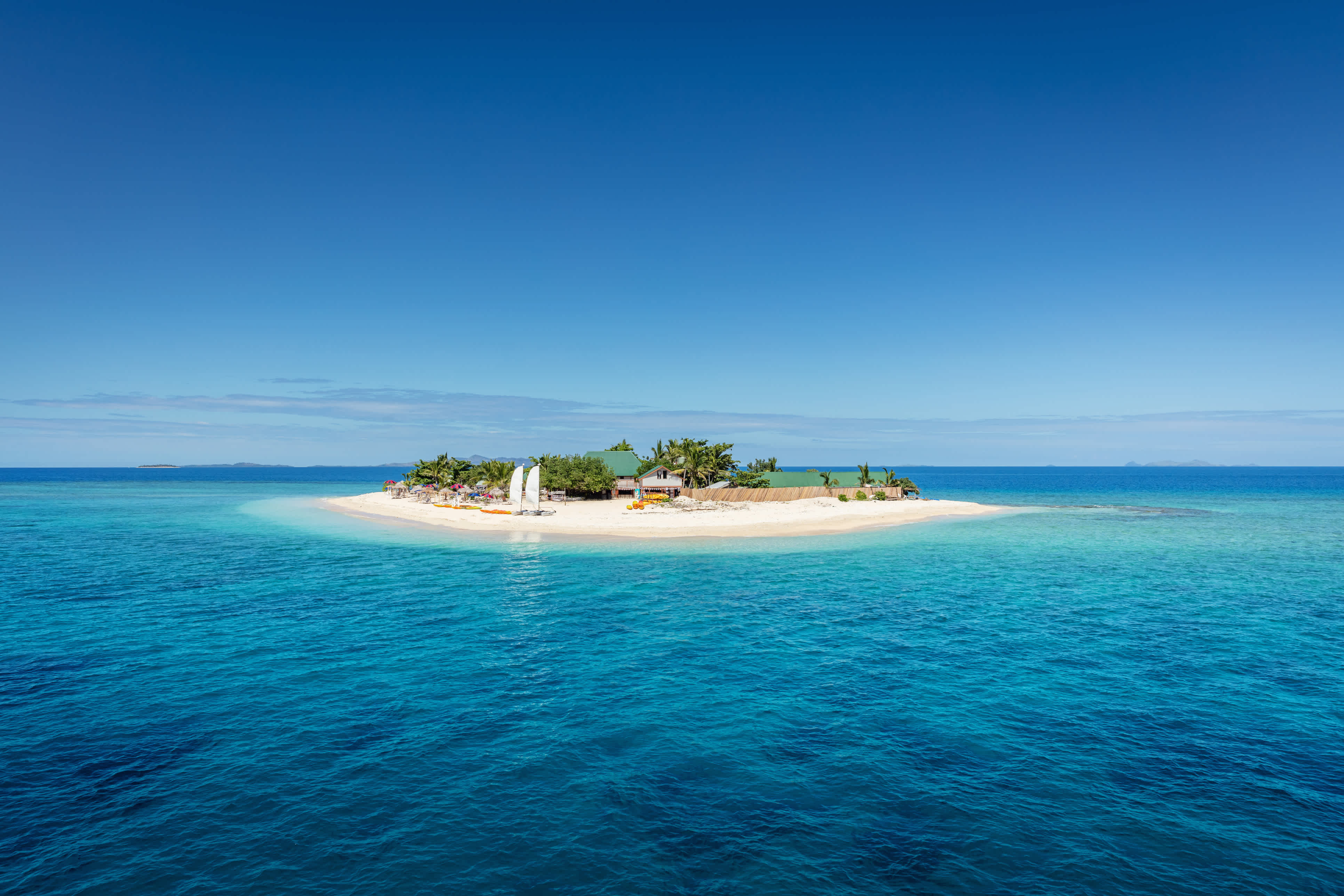 Schöne kleine Insel mitten im Südpazifik mit Strandhütten, Liegestühlen, Palmen, umgeben von wunderschönem klarem türkisfarbenem Wasser. Inselchen, Mamanuca-Inseln, Fidschi, Melanesien