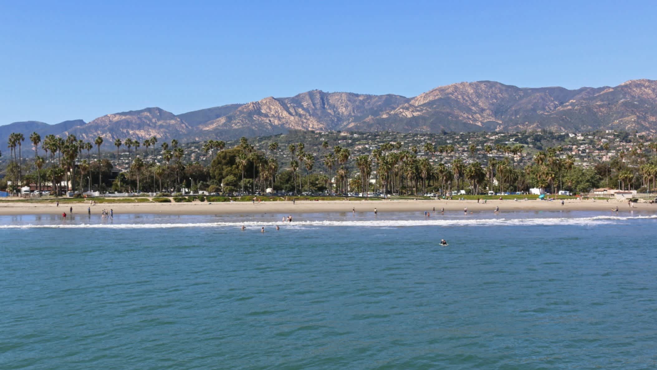 Weitblick auf den Strand East Beach, Santa Barbara, Kalifornien, USA bei Sonnenschein und mit der Stadt sowie Bergen im Hintergrund.
