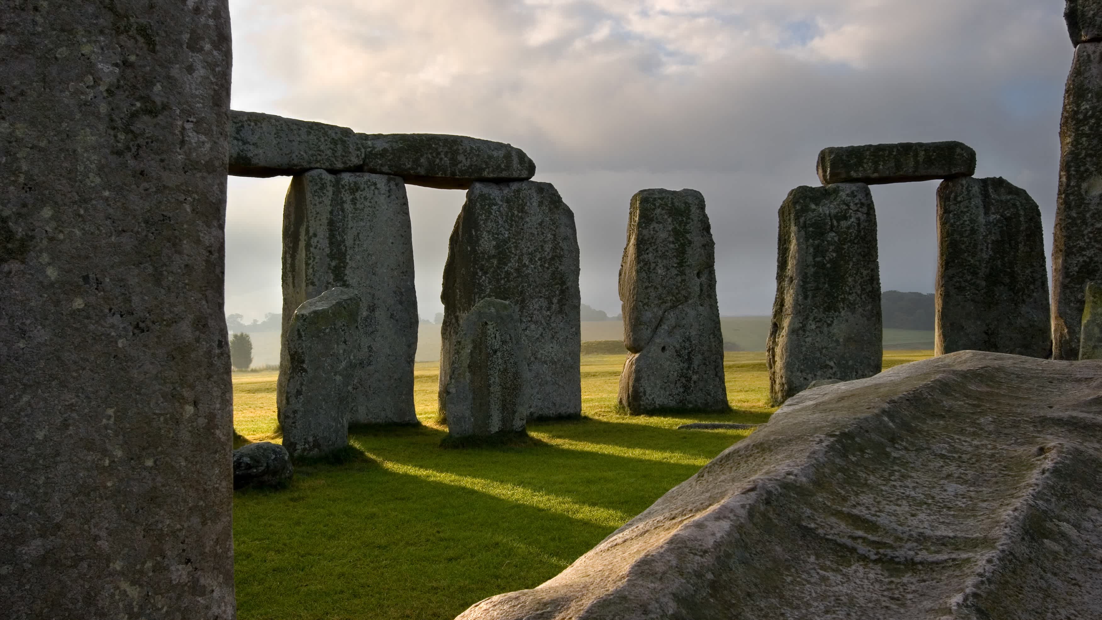 Die Sonne geht auf und wirft ihre Strahlen durch die massiven, handgeschnitzten Steine von Stonehenge, das vor Tausenden von Jahren in der Salisbury-Ebene errichtet wurde. England, Großbritannien.