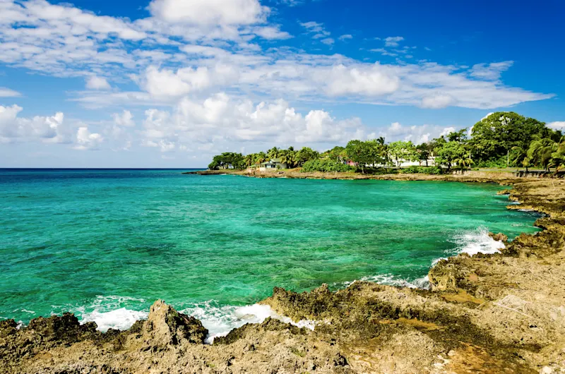 San Andrés, Caraïbes, Colombie Côte tropicale avec eau turquoise, rochers côtiers, végétation luxuriante et petites maisons, San Andrés, Colombie.