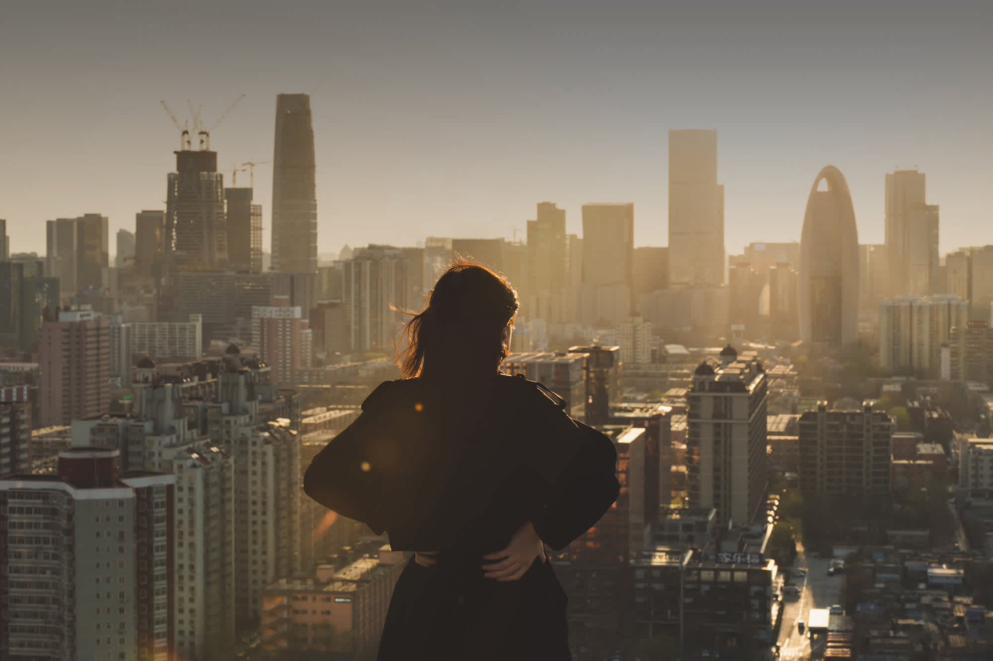 Une femme photographiée de dos, regarde la skyline de la ville de New York aux États-Unis.