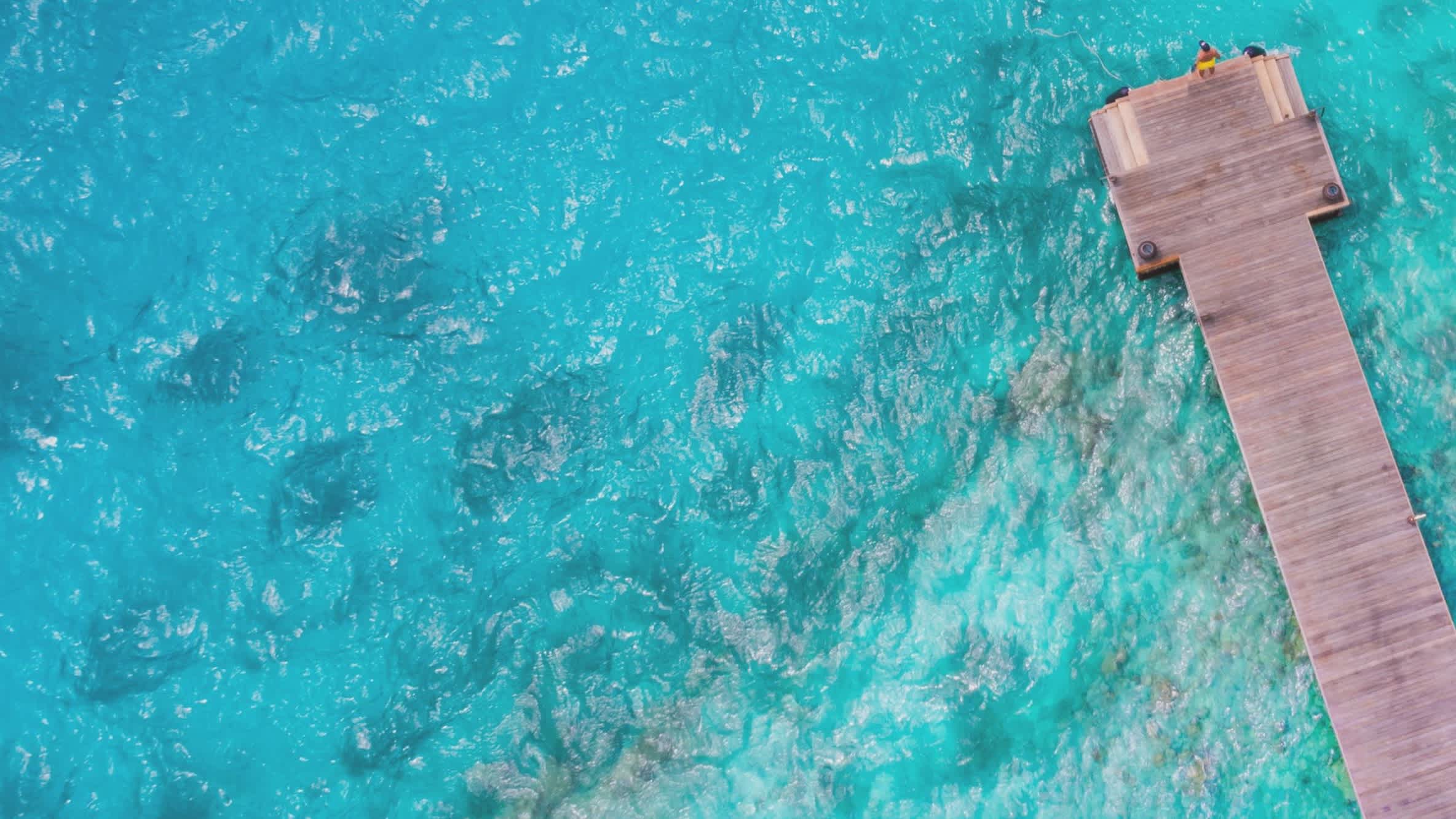 Voyageur sur la jetée près à sauter dans l'eau à Kuda Hithi aux Maldives.