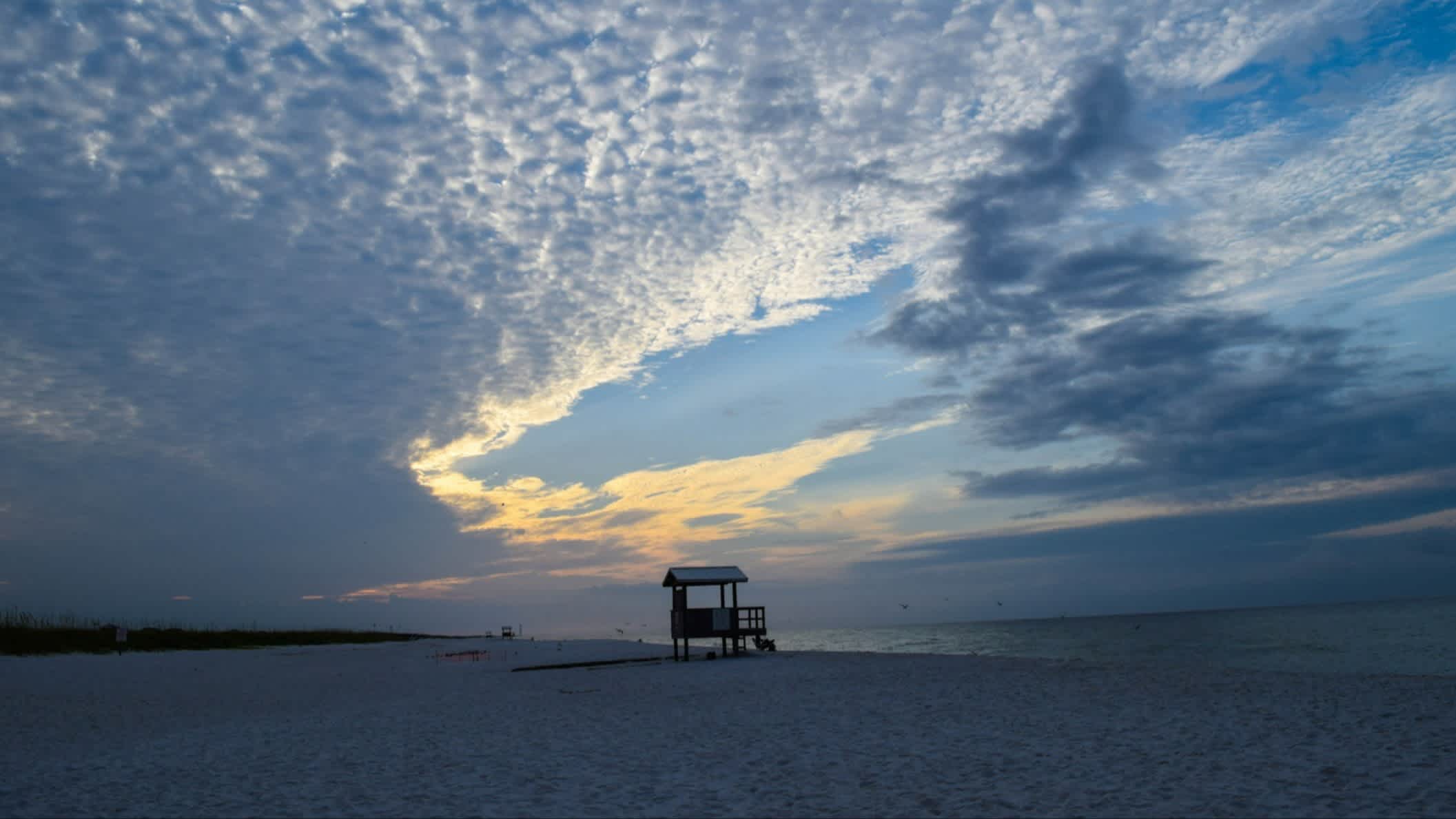 Der Strand Navarre Beach, Santa Rosa County, Florida, USA bei Dämmerung und mit Blick auf einen Wachturm am Strand. 