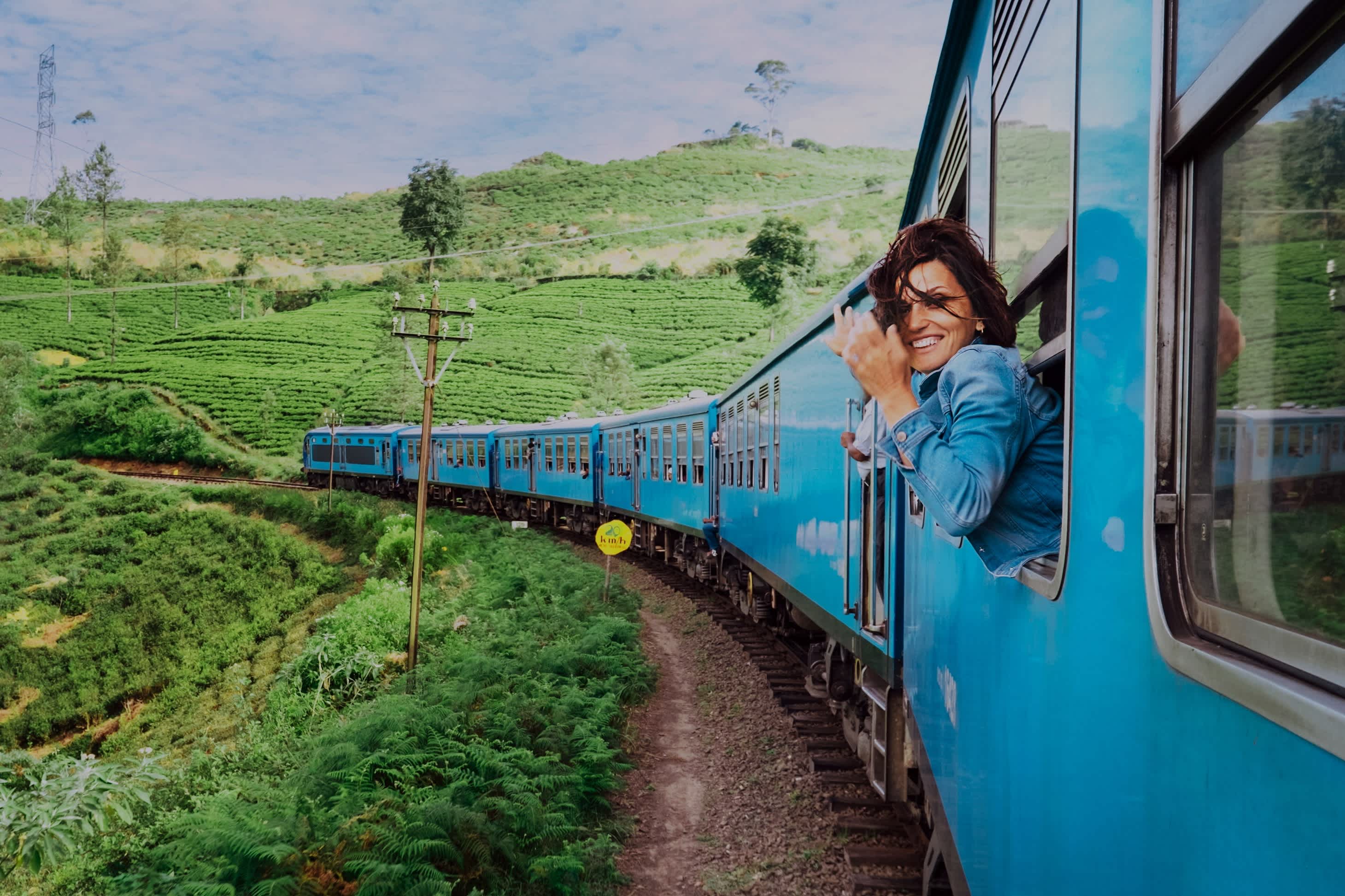 Lächelnde Frau schaut aus Fenster Reisen mit dem Zug unterwegs malerischsten Zug in Sri Lanka.