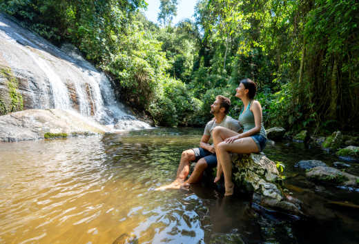 Fröhliches Wandererpaar mit Blick auf einen schönen Wasserfall in Brasilien 