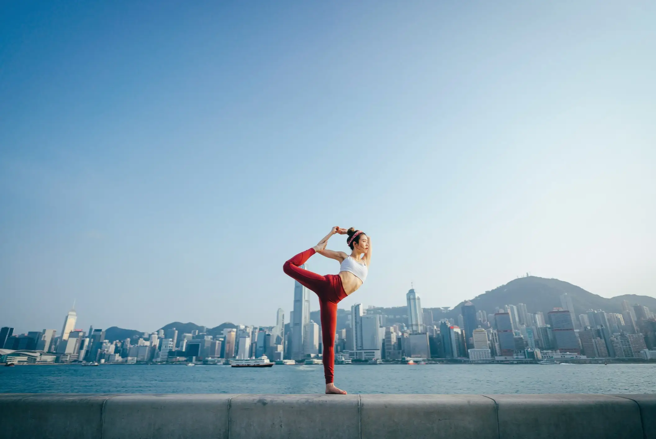 Une femme fait du yoga avec la ville d'Hong Kong en arrière-plan.