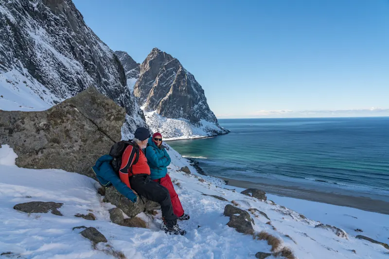 Zwei Personen auf Bergpass am Winterstrand von Kvalvika, Lofoten

